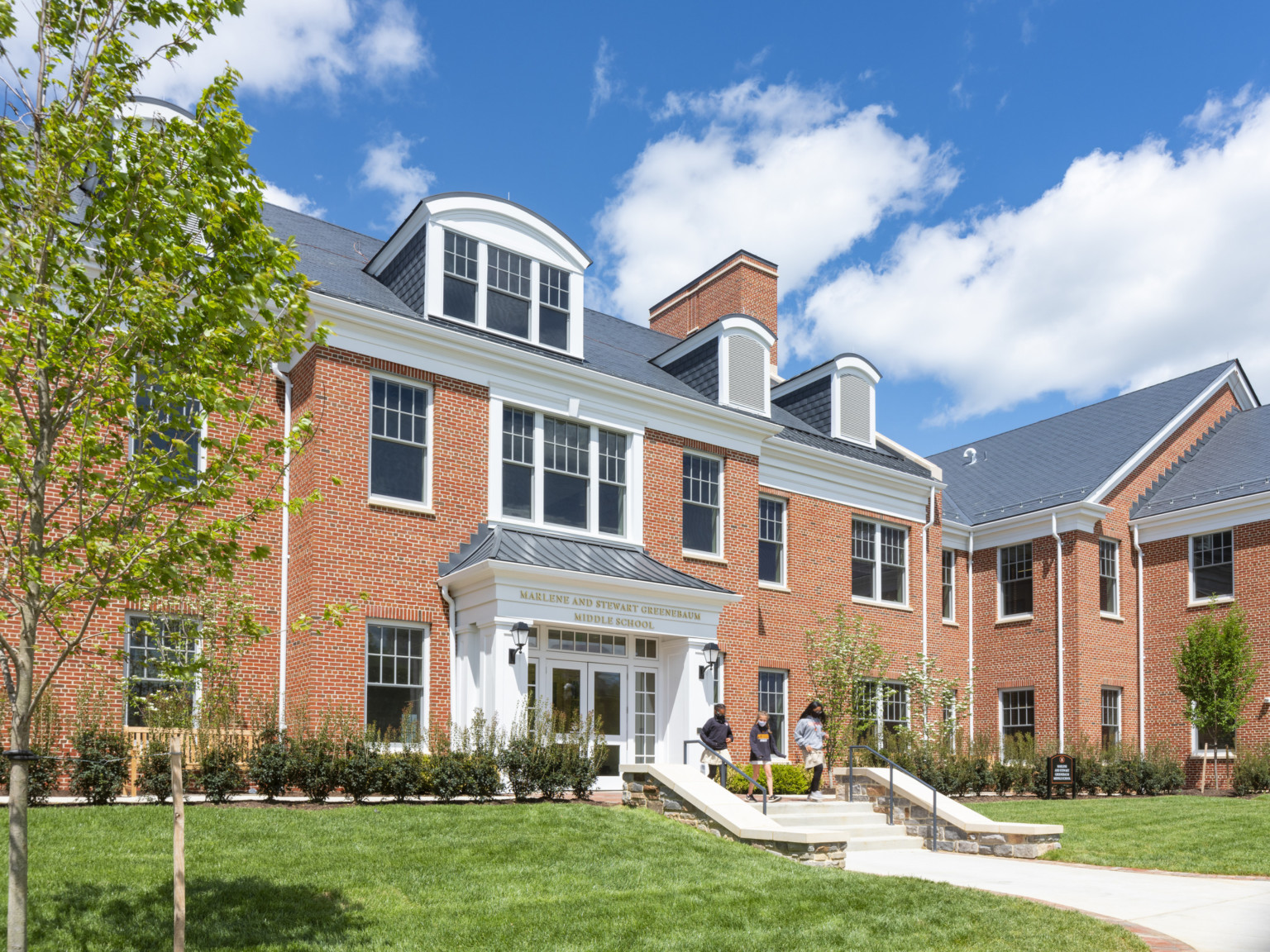 Brick colonial style building with white entry and glass doors with sign reading Marlene and Stewart Greenebaum Middle School