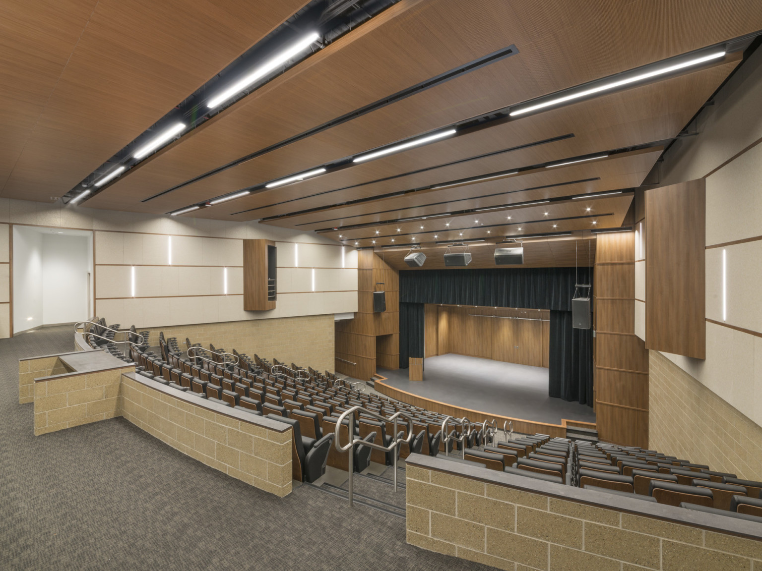 600 seat auditorium with wood acoustic panels overhead and framing stage with black curtains