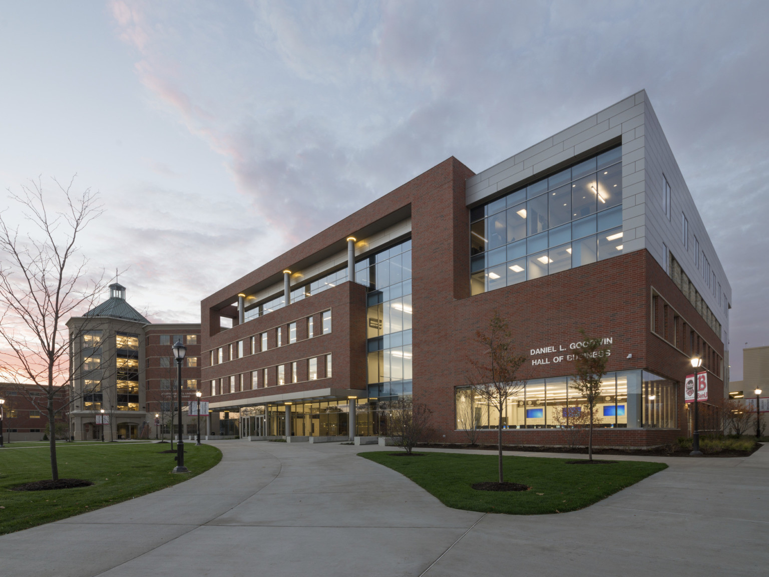 Exterior corner of brick and white panel wrap facade building with Daniel L. Goodwin Hall of Business sign over large windows