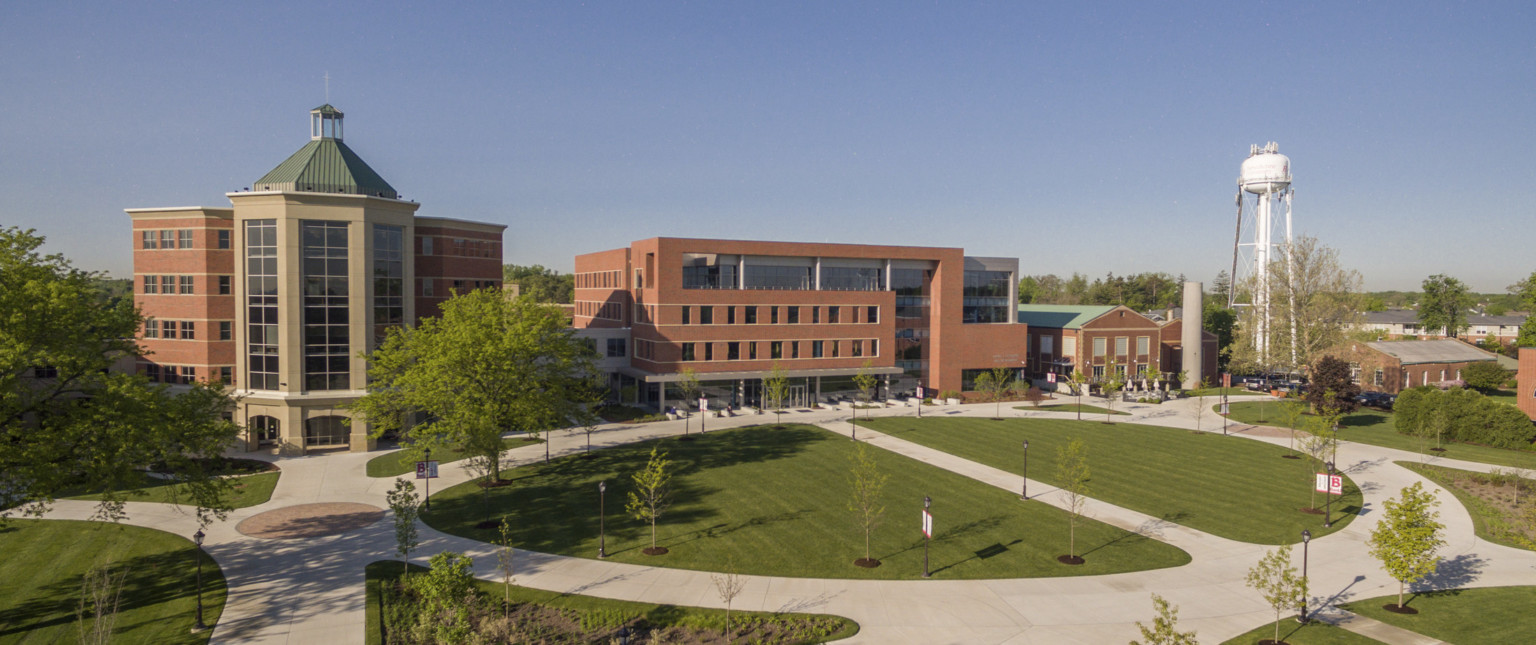 exterior view of Goodwin Hall from across the Quad with grass, trees, and paths to brick wrapped facade building, large windows