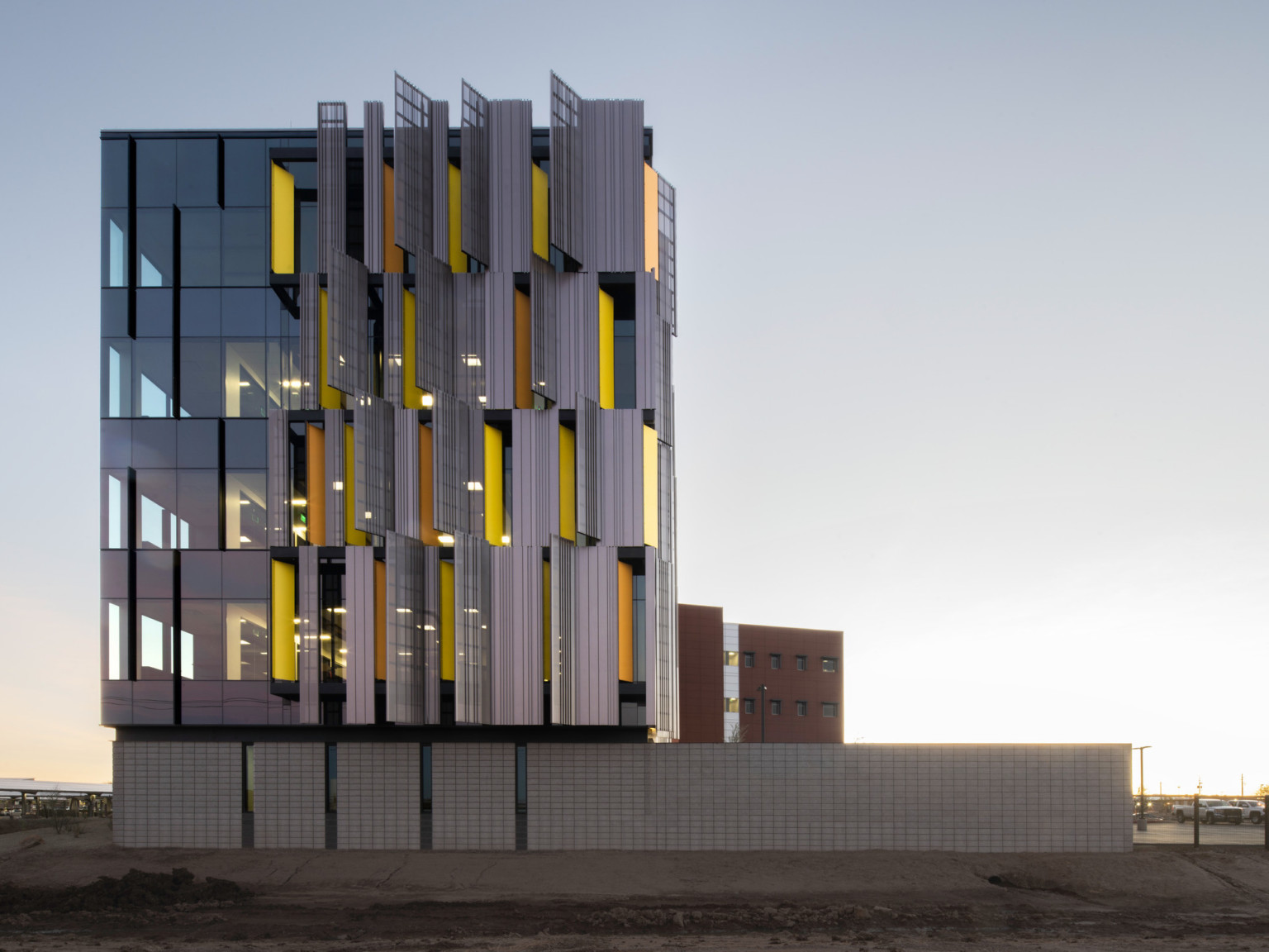 side view of courthouse with serrated sunscreen facade, a pattern of yellow panels peaking between. Floor to ceiling windows