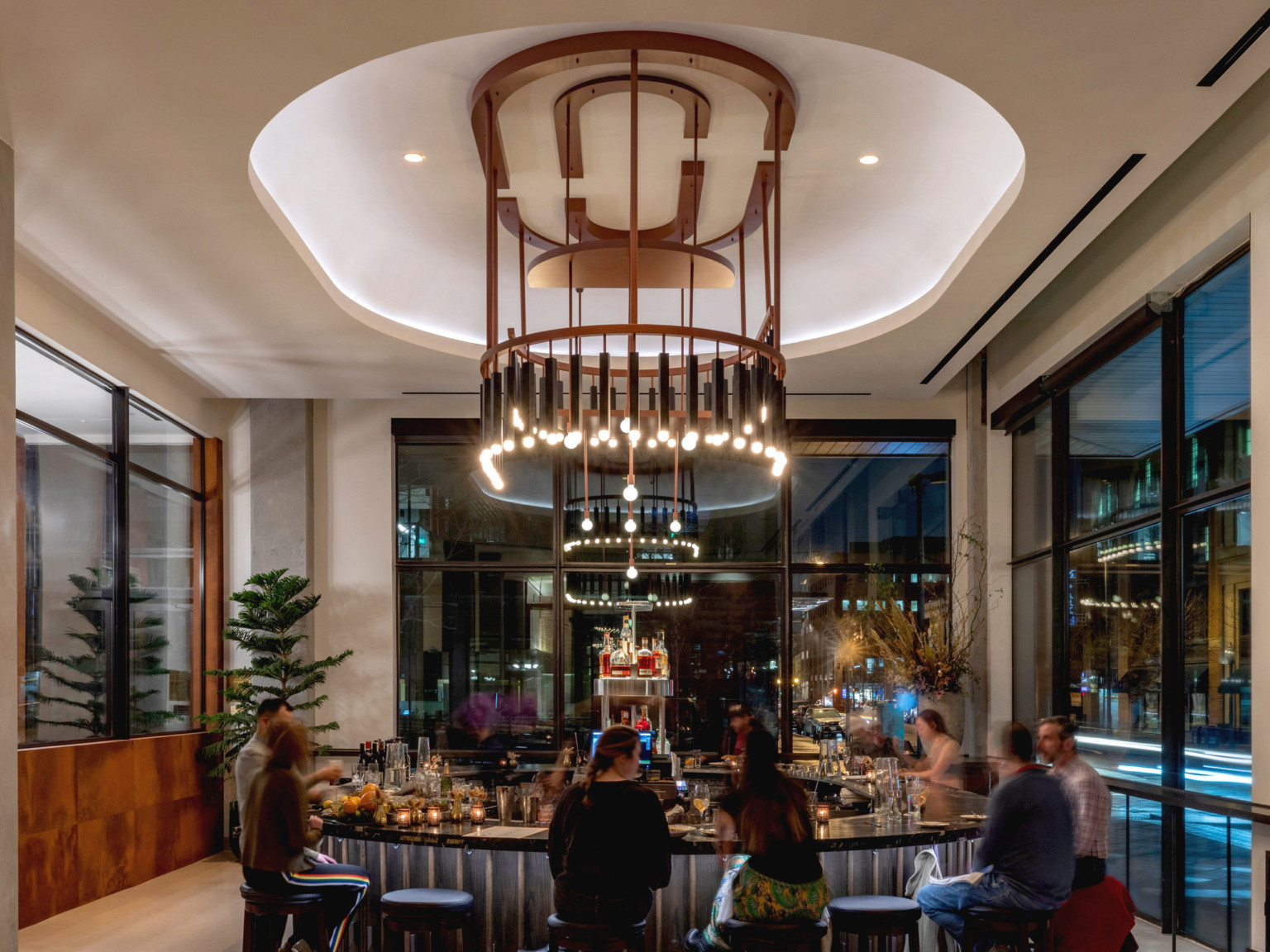 Interior of the same lounge space. Round bar at center, shape mirrored with recessed ceiling and elaborate modern chandelier