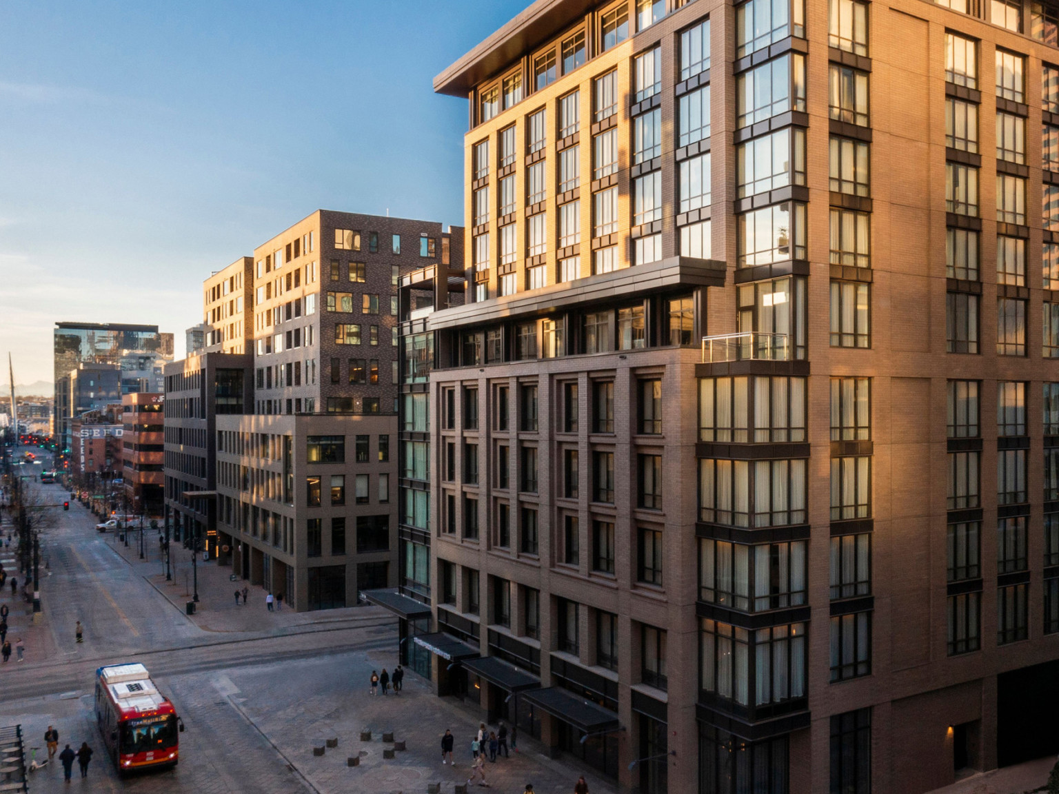 Wide pedestrian walkway at the base of the brutalist hotel with large windows and exposed steel accents