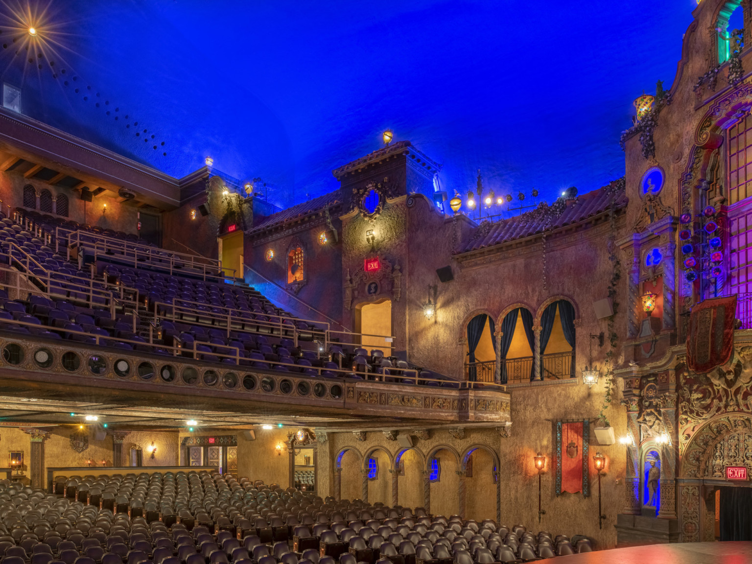 Theater interior from stage looking to audience chamber and 2 story wall with illusion windows lit in blue from behind