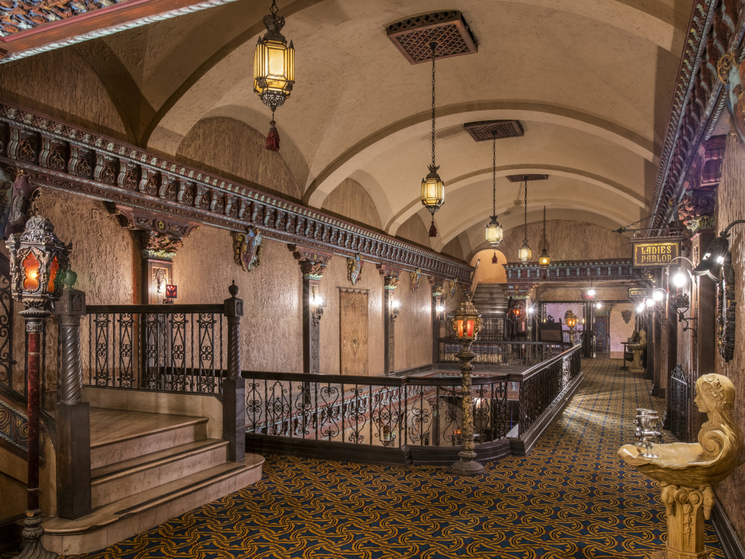 Mediterranean style mezzanine hallway with painted carved wood mouldings, arched ceiling, sculptural water fountain, pendant lamps