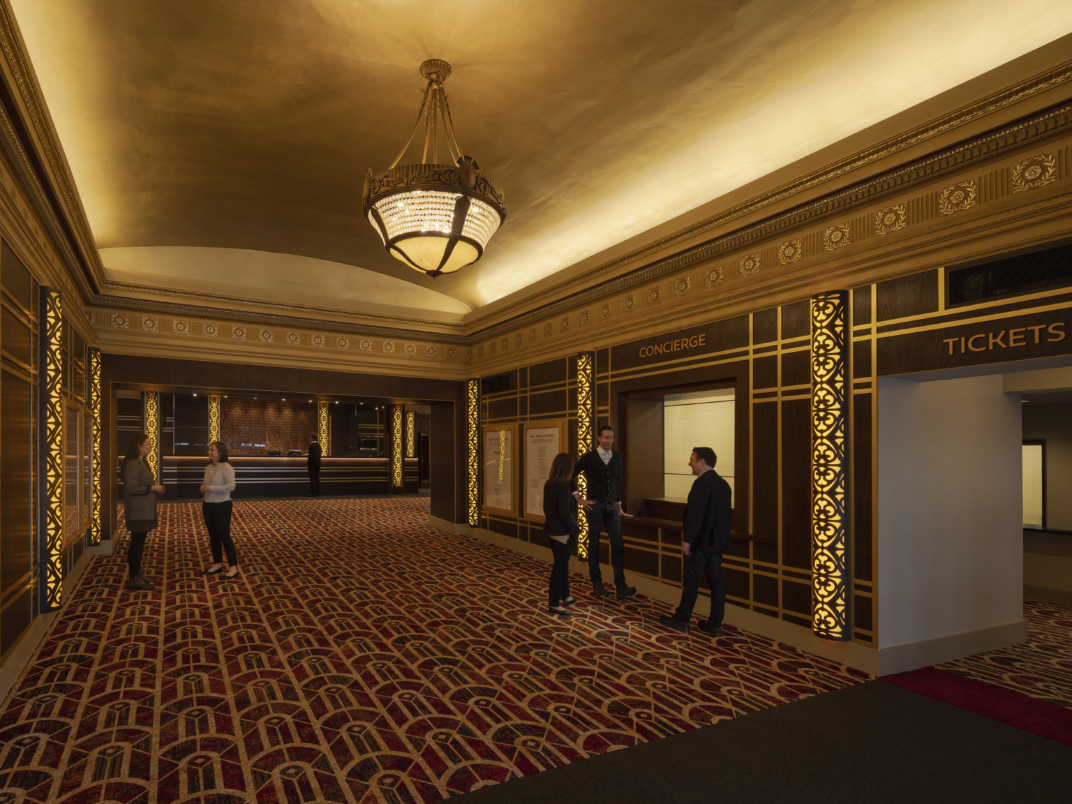 Art deco lobby with concierge and ticket booths. Carved wood wall mouldings, domed rectangular ceiling with chandelier