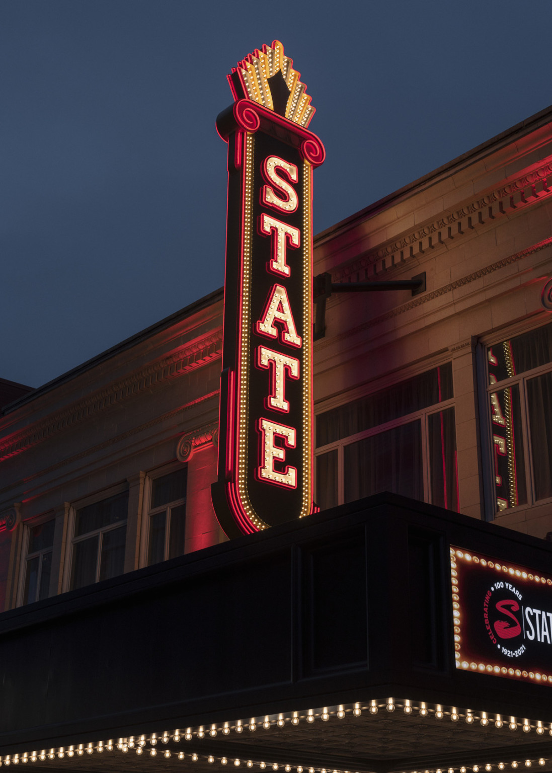 Closeup of recreation vintage of illumnated blade sign reading State, at night