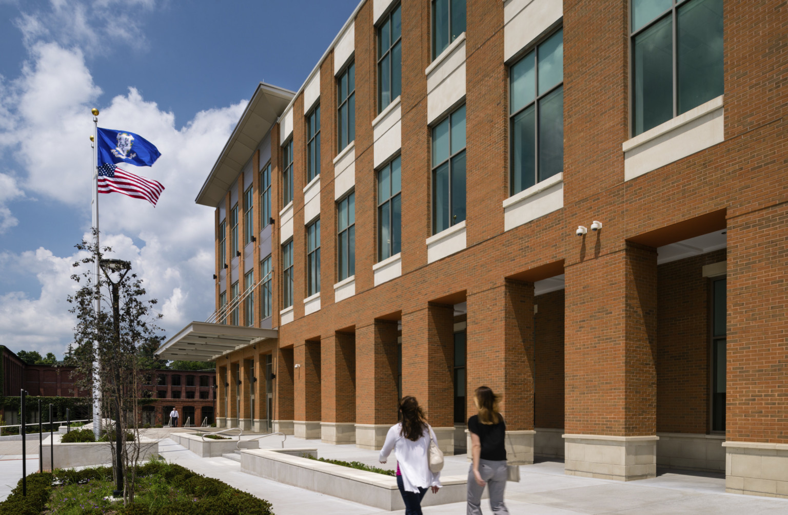 Exterior of brick courthouse with flags waving to left, large windows framed with beveled masonry to right