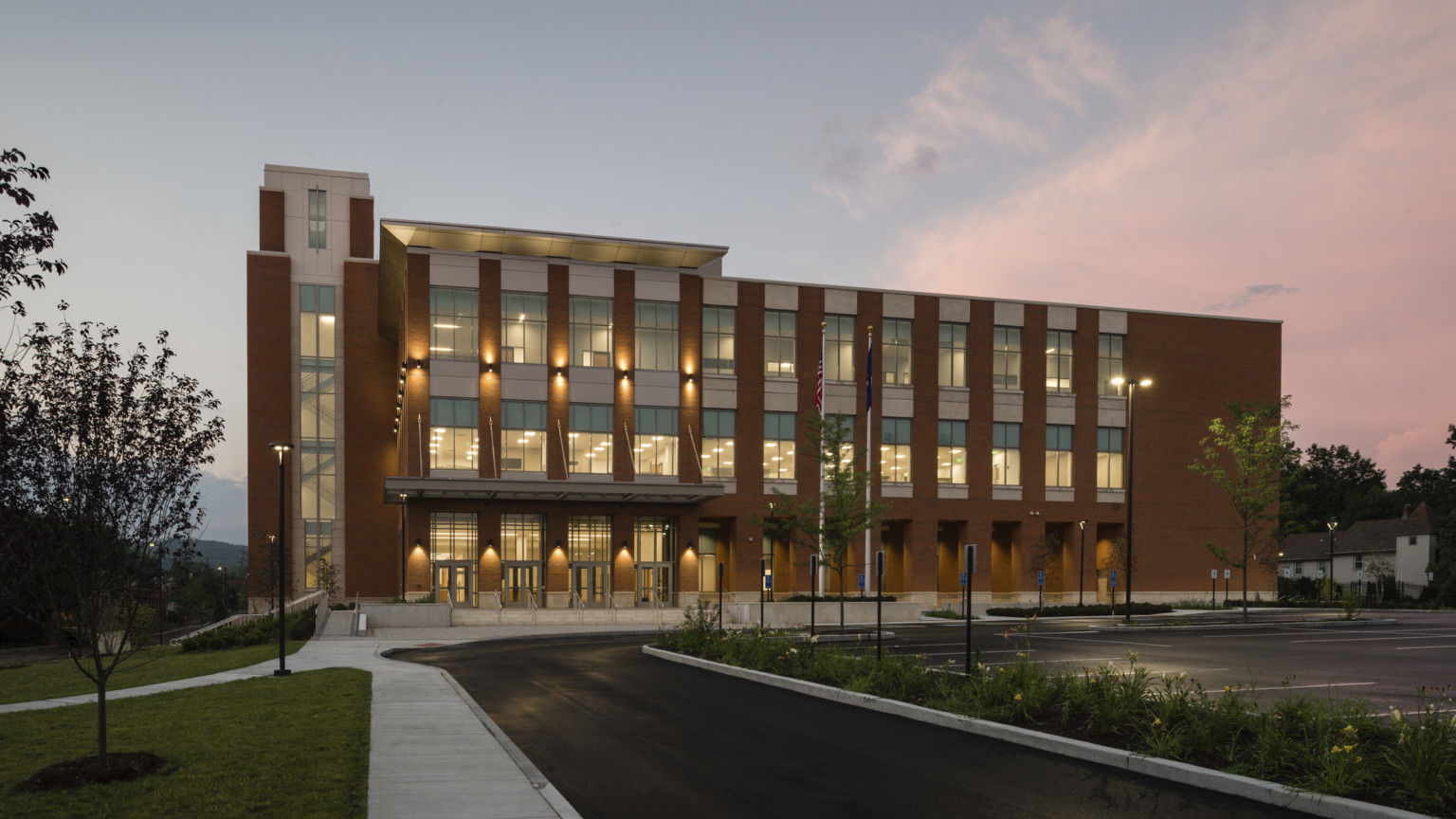 Litchfield Judicial District Courthouse illuminated in the evening from within, a brick building with winding sidewalk to entry