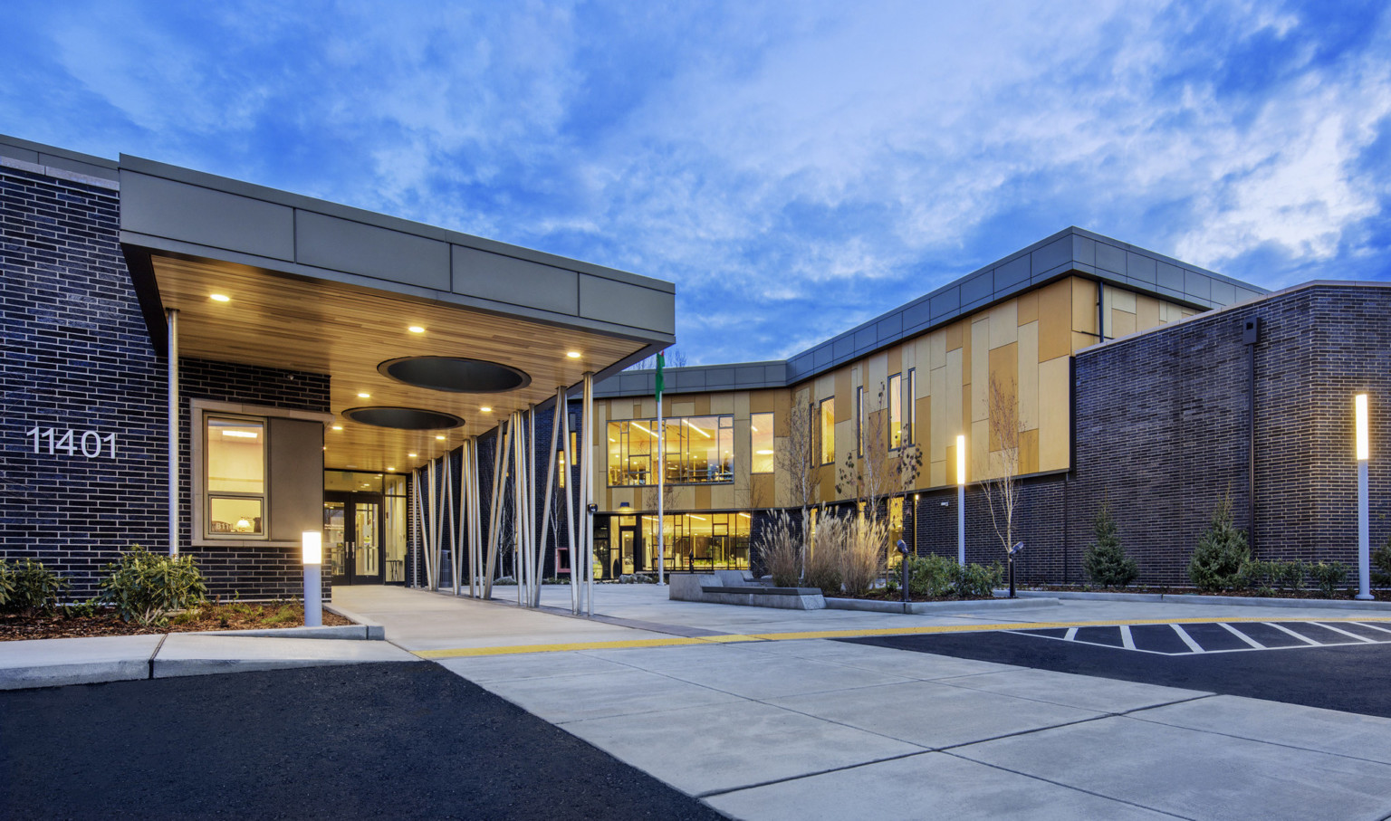 Building entrance viewed from driveway. The building dark brick with wood panel details