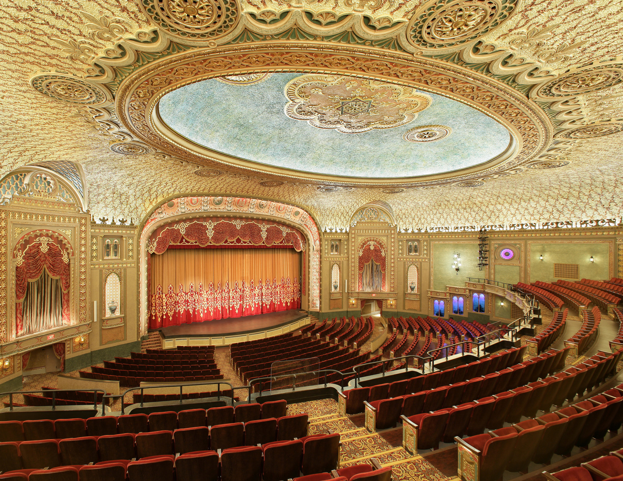 Interior of the Tennessee Theater, seen from the balcony looking to stage, ornate golden-patterned ceiling with round, recessed detail, dark red theatre seating