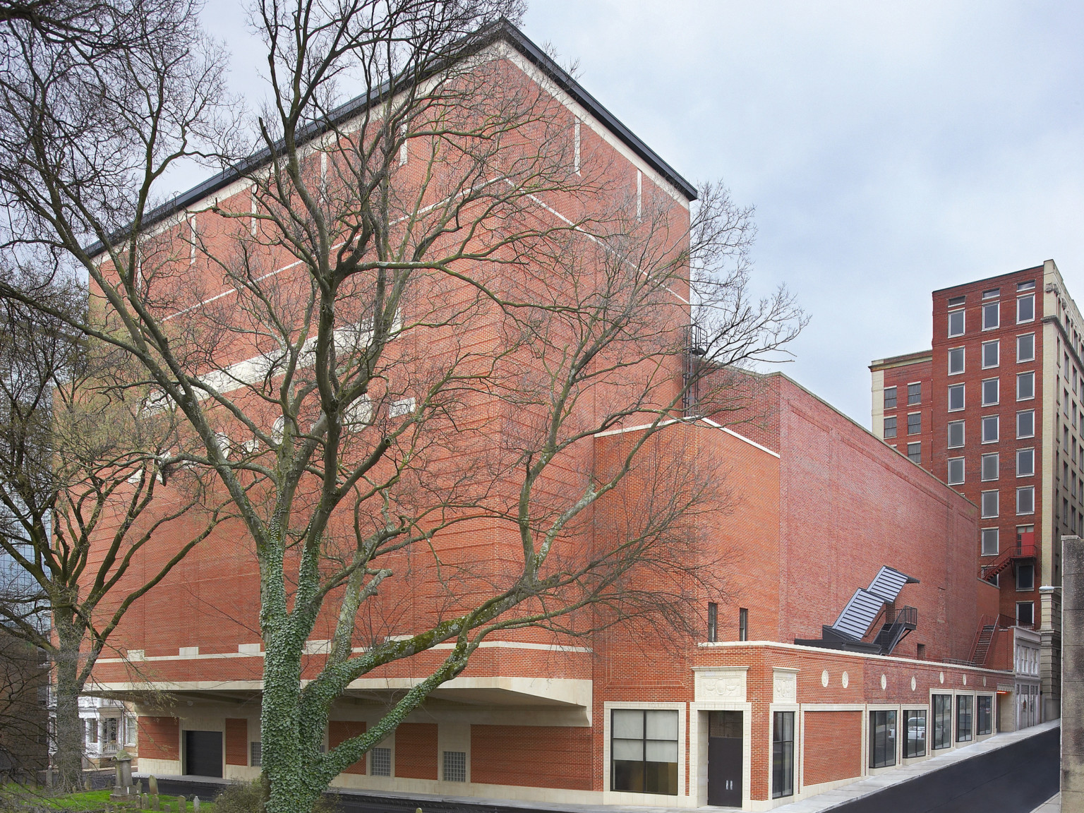 Exterior corner view of multistory brick building with windows along one wall of first story