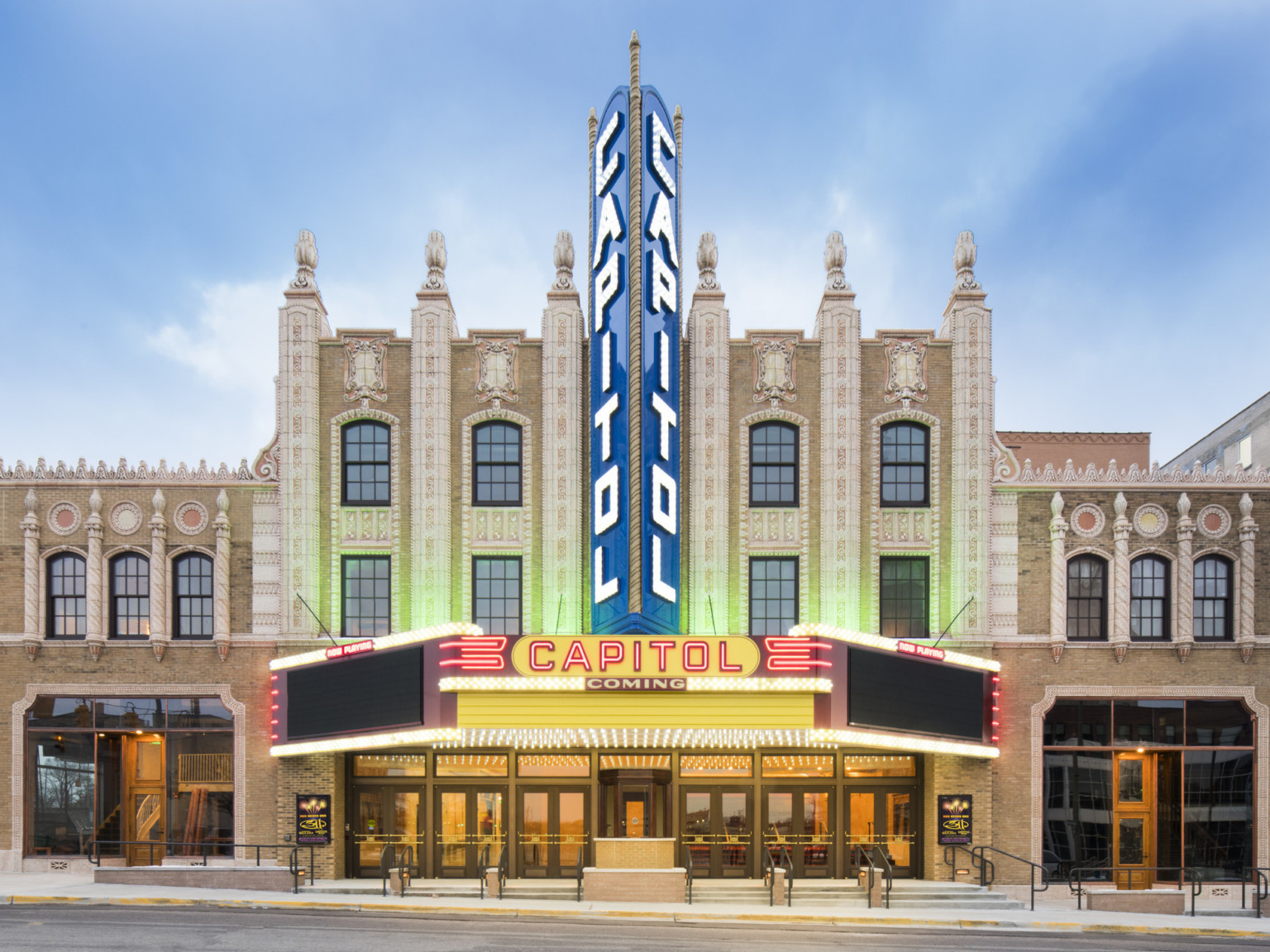 Capitol Theatre front entry with vintage neon marquee and blade sign on carved white low relief facade on beige stone