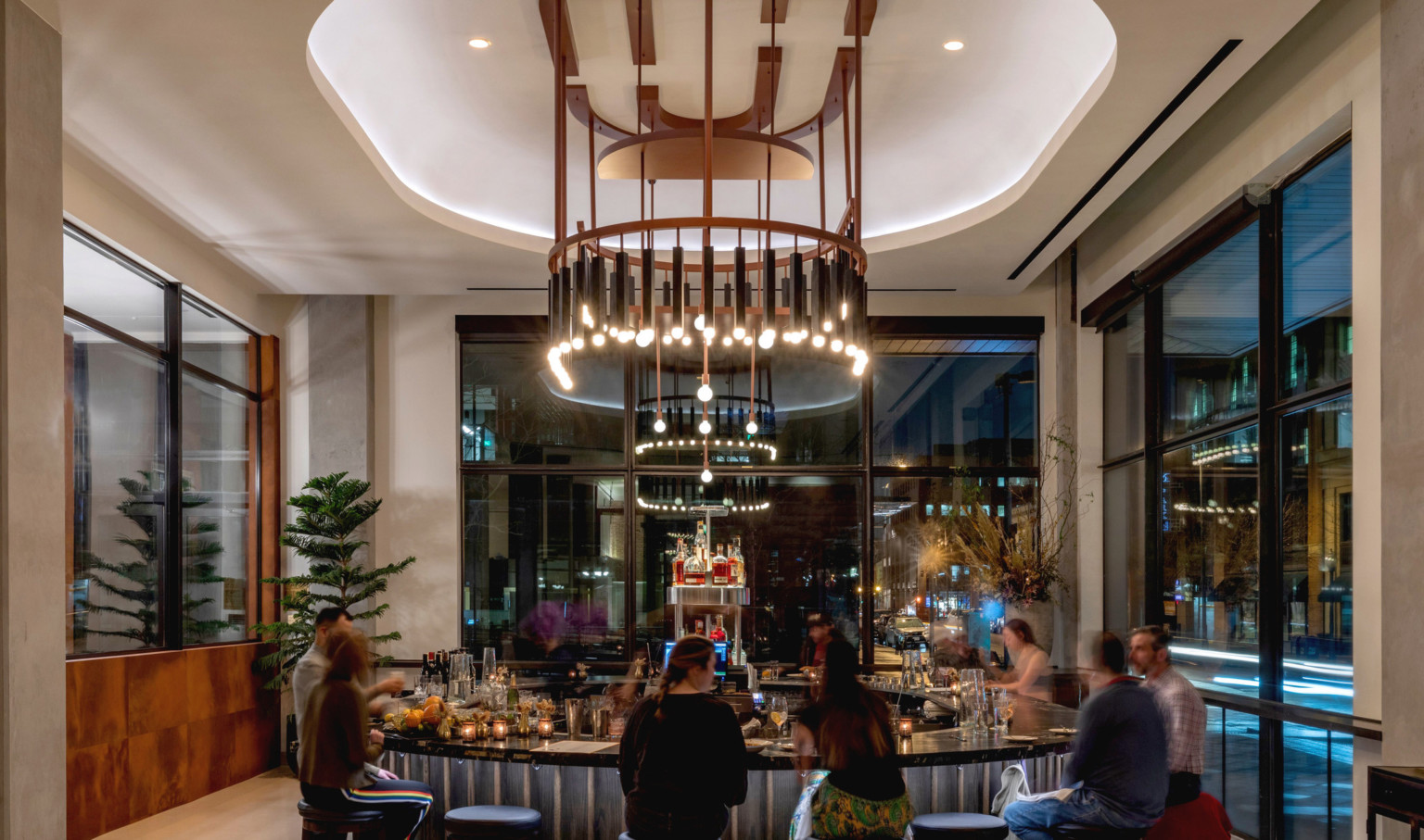 Interior of the same lounge space. Round bar at center, shape mirrored with recessed ceiling and elaborate modern chandelier