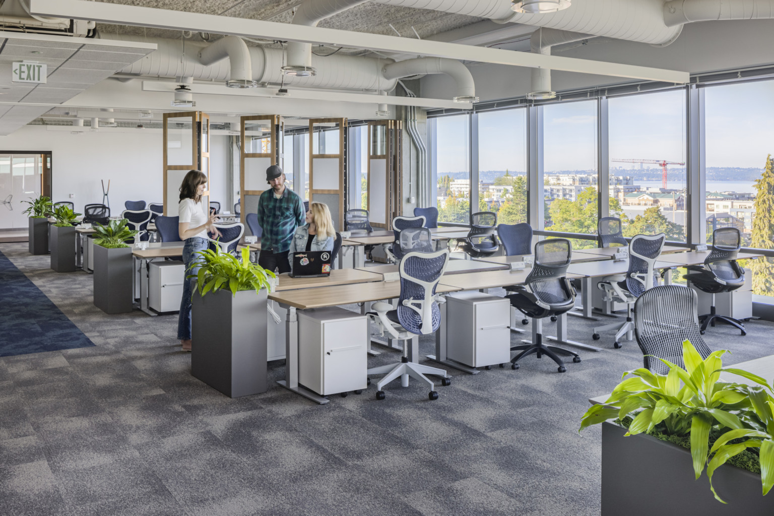 Office interior with SpaceShift flexible wall to the back, greenery, and large windows