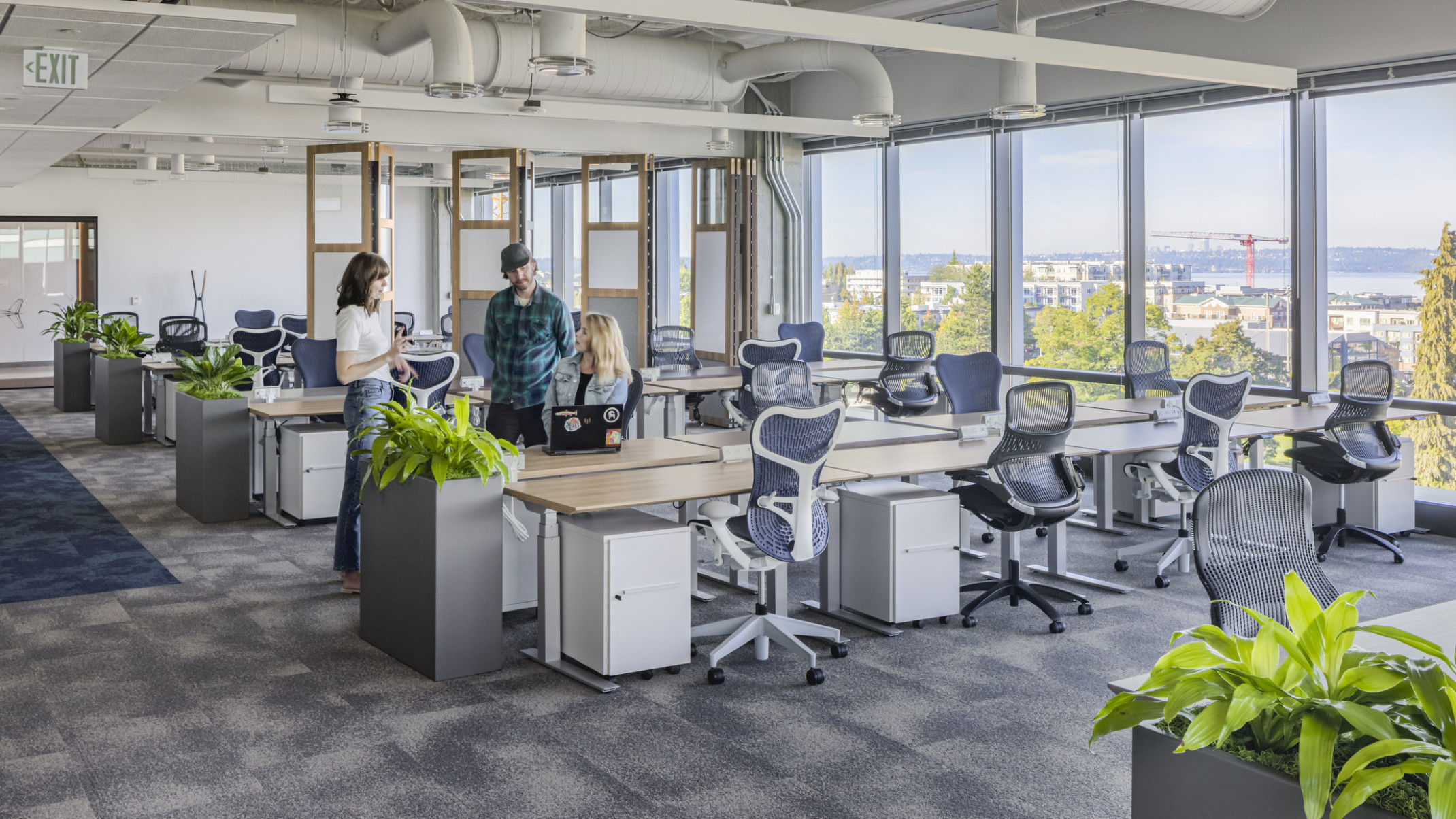 Office interior with SpaceShift flexible wall to the back, greenery, and large windows