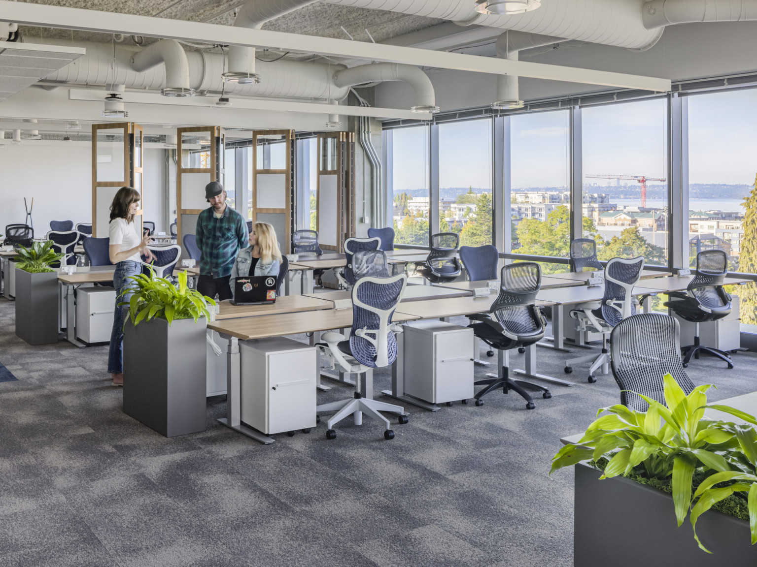 Office interior with SpaceShift flexible wall to the back, greenery, and large windows