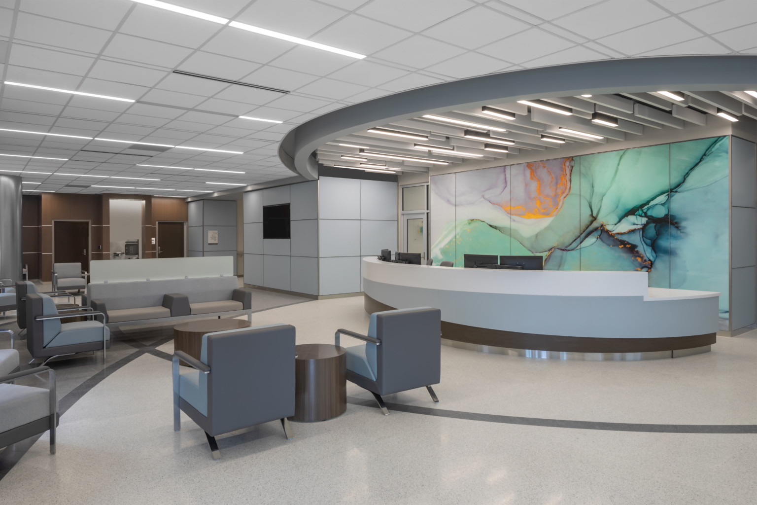 Waiting area lobby with long rounded reception desk in front of marbled wall mural in green with gold and purple accents