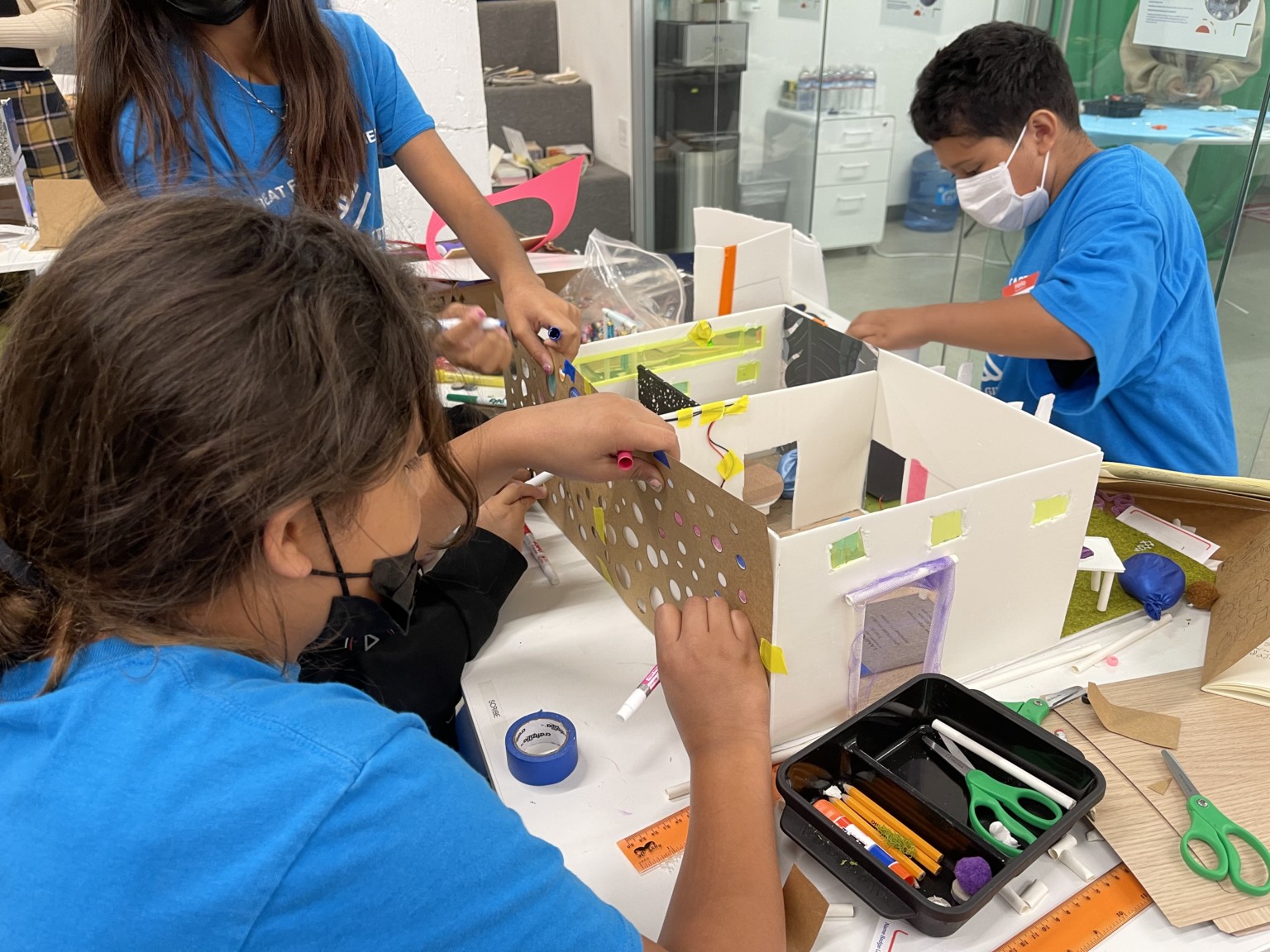 three students building an architectural model