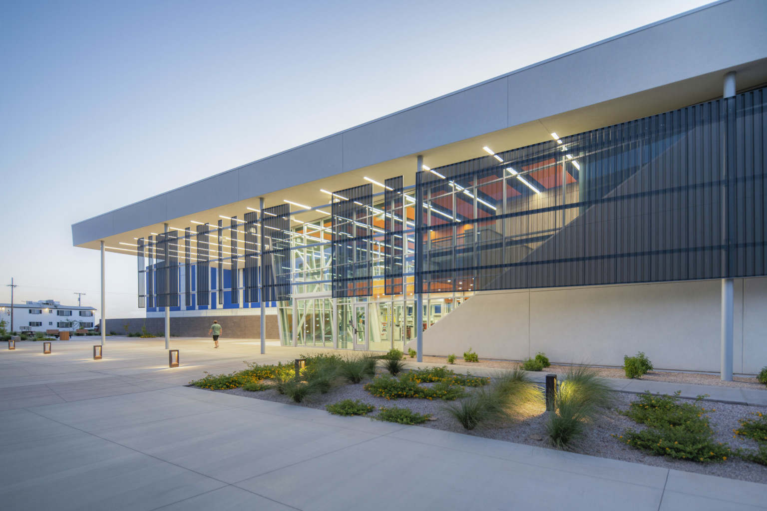 low rise industrial style building with glass facade, blue and orange interior, corrugated vertical fins and exterior stair