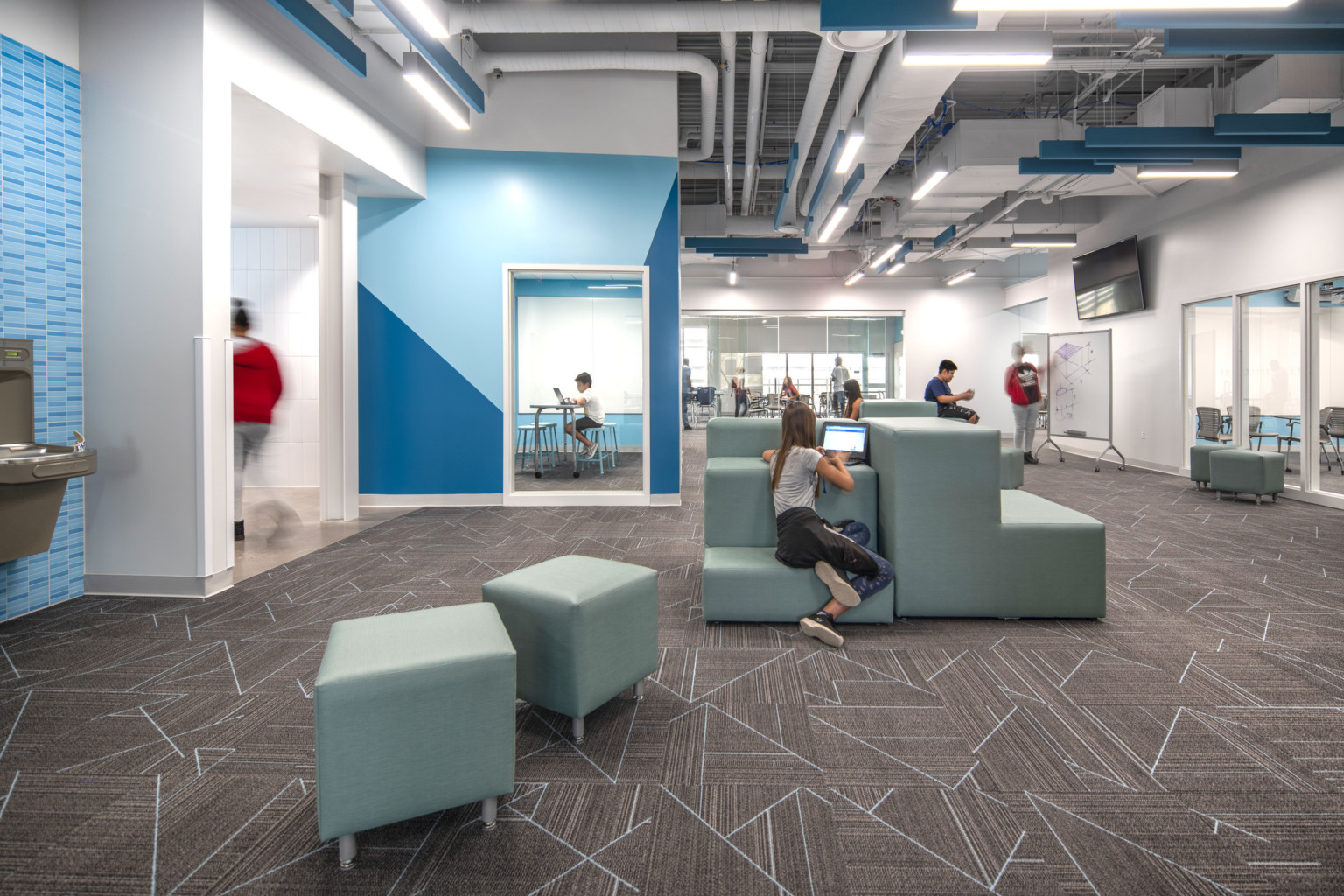 Moveable, modular furniture fills the space of a middle school with a study room in the background, white boards line the walls