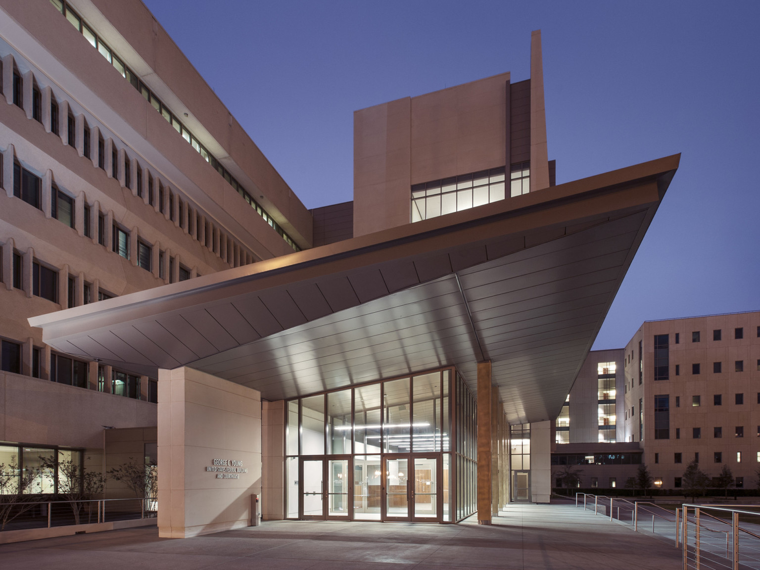 illuminated federal building at night with large sculpture on the lawn