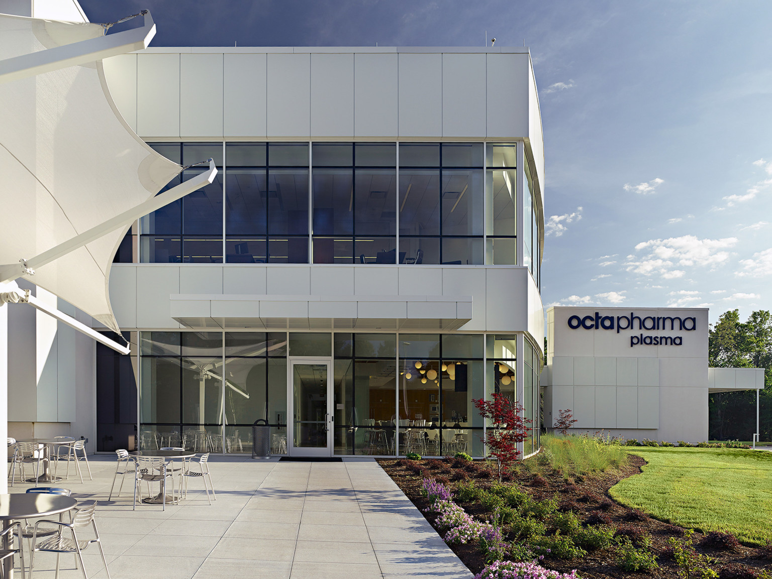 daytime view of a courtyard outside a two story office building with landscaping and a large white swirling sculpture