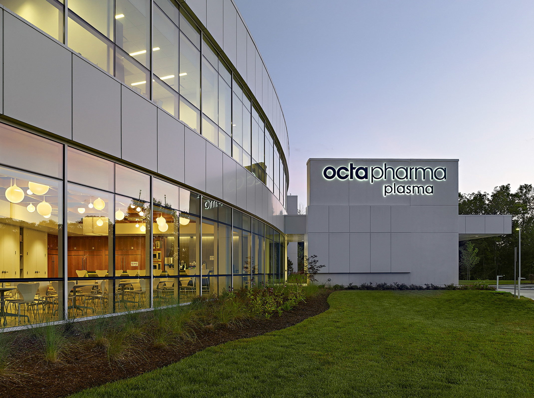 evening view of a double height glass facade with Octapharma logo on the far building wall