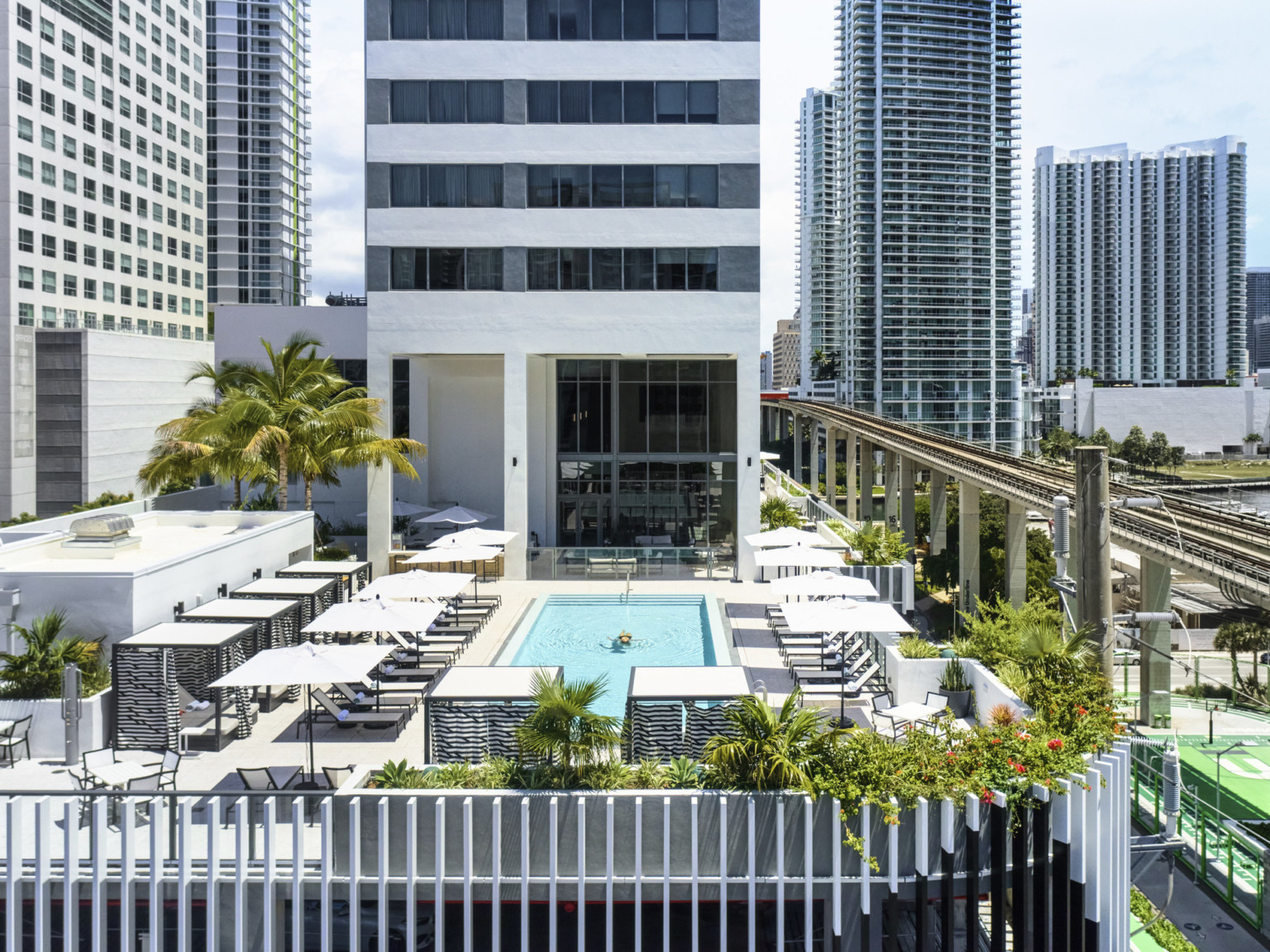 View of sky pool at AC Hotel by Marriott & Element Miami Brickell surrounded by bustling city, adjacent Biscayne Bay, Miami River