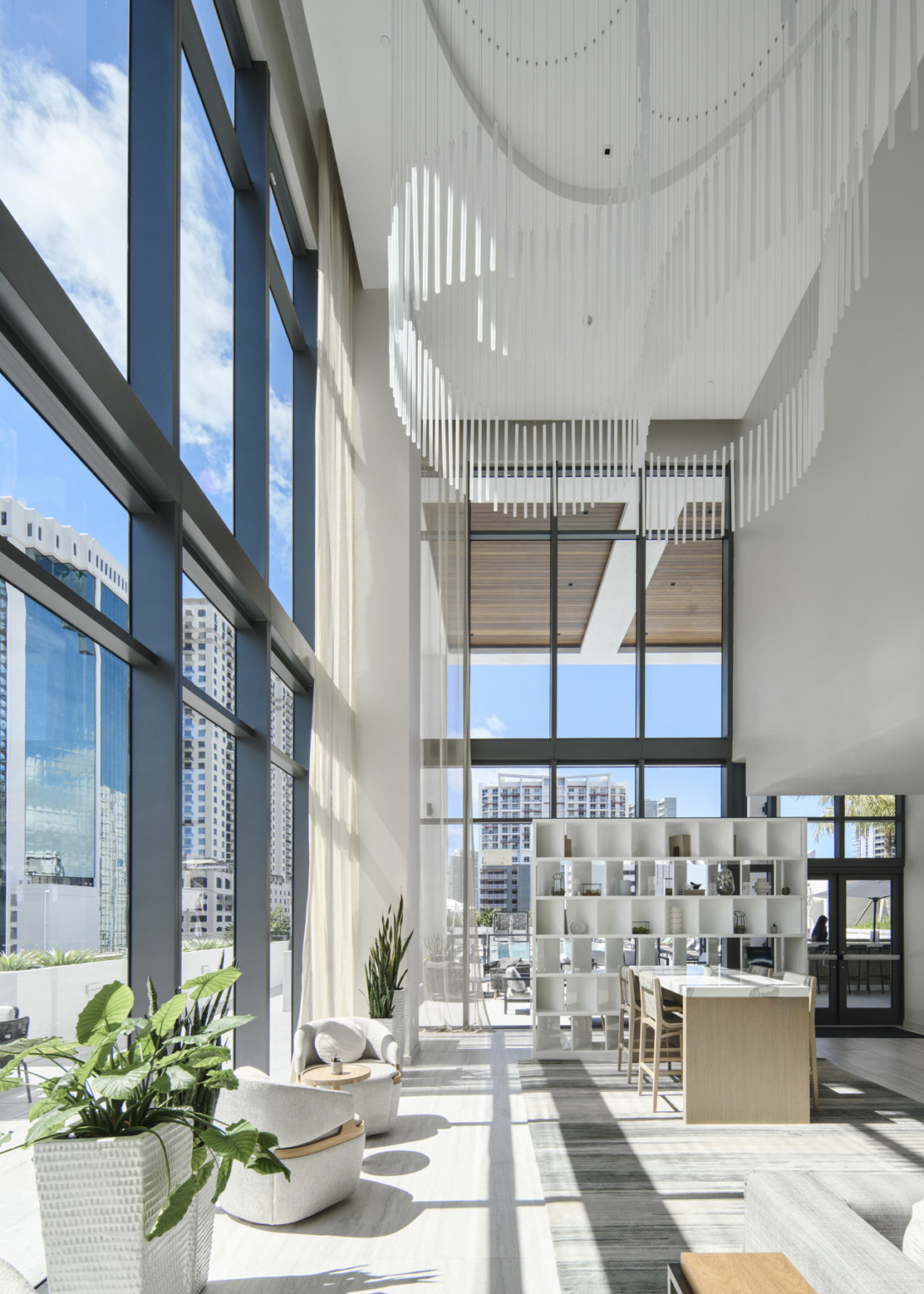 Opaque glass sculpture hangs over double-height lounge area surrounded by the 6th floor exterior terrace with outdoor lounge spaces