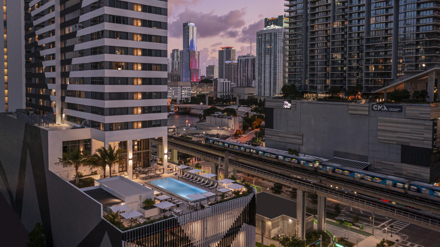 AC Hotel by Marriott & Element Miami Brickell, a tall tower with midlevel patio and outdoor pool with seating area in downtown Miami surrounded by tall buildings