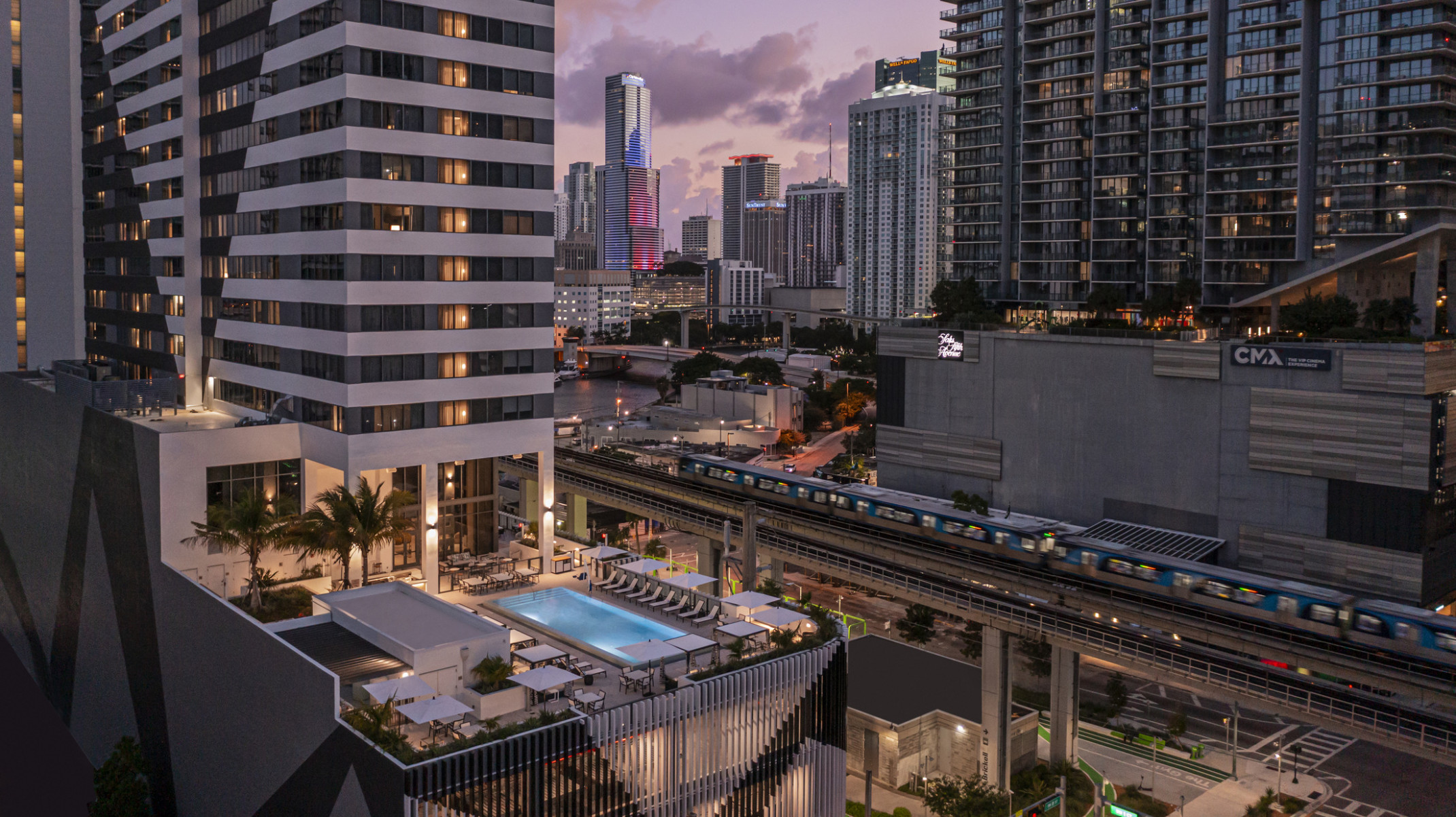 AC Hotel by Marriott & Element Miami Brickell, a tall tower with midlevel patio and outdoor pool with seating area in downtown Miami surrounded by tall buildings