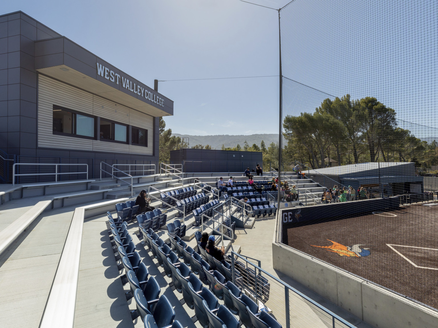 Rows of bleacher around softball field with Viking emblem behind home plate. Press box at center back