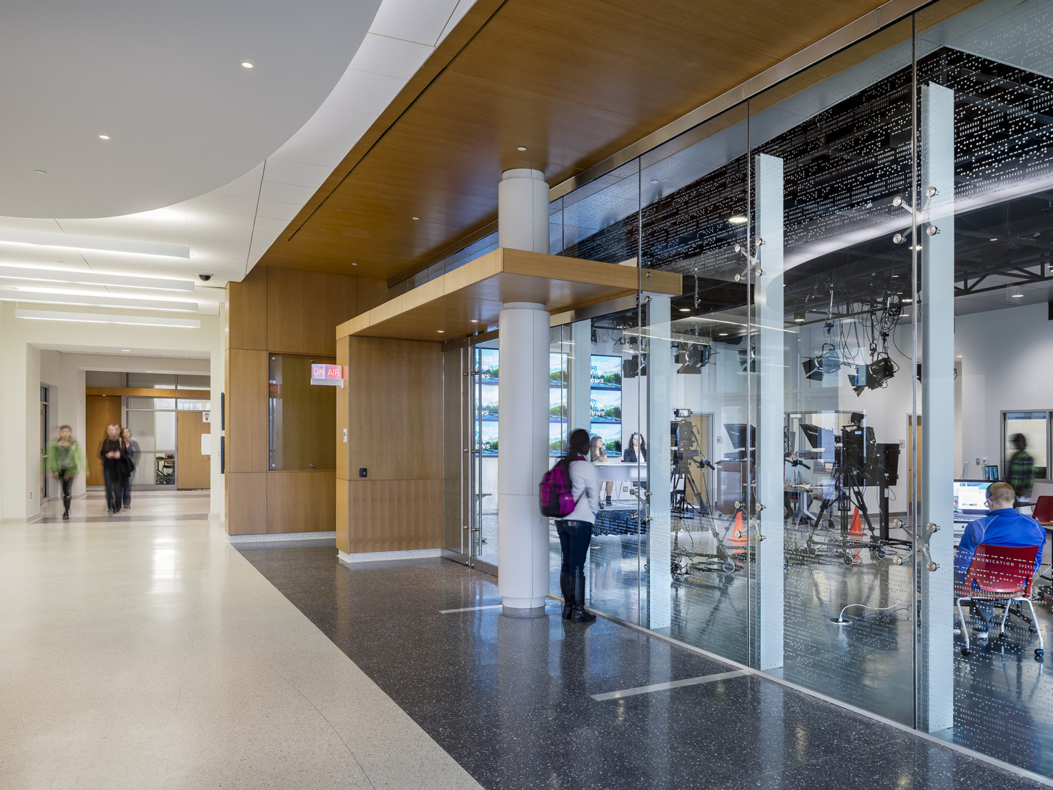 white floor and curved white ceiling over blond wood framed classroom entrance with floor to ceiling glass walls