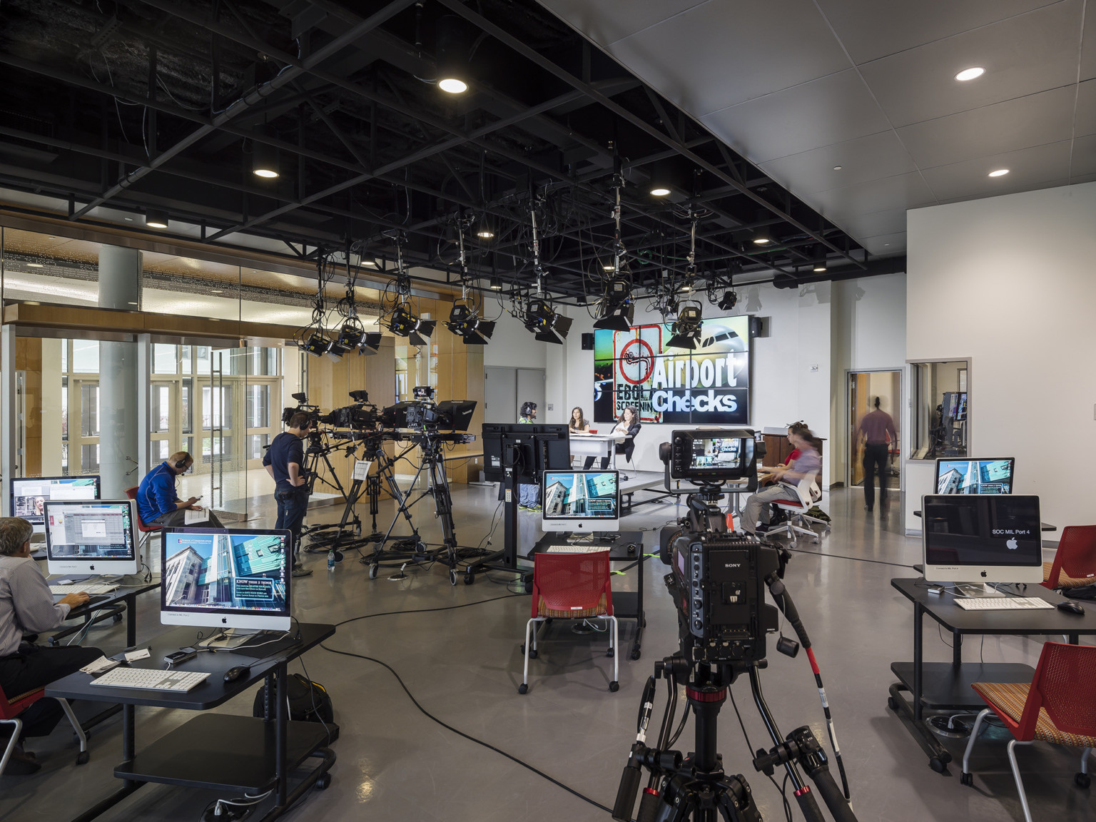 media lab with black perforated ceiling, suspended audio equipment movable desks with media screens and red chairs on casters