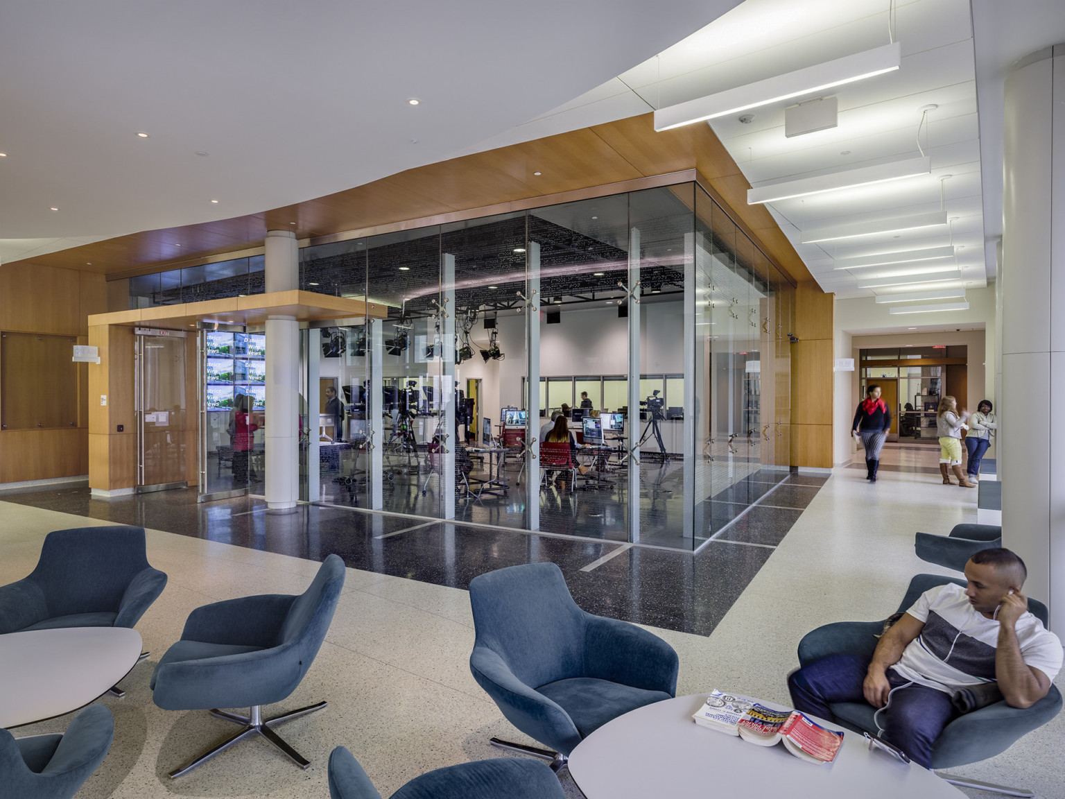 white ceiling and terrazzo floors and wood frame around glass walled media room. soft seating clusters around the perimeter