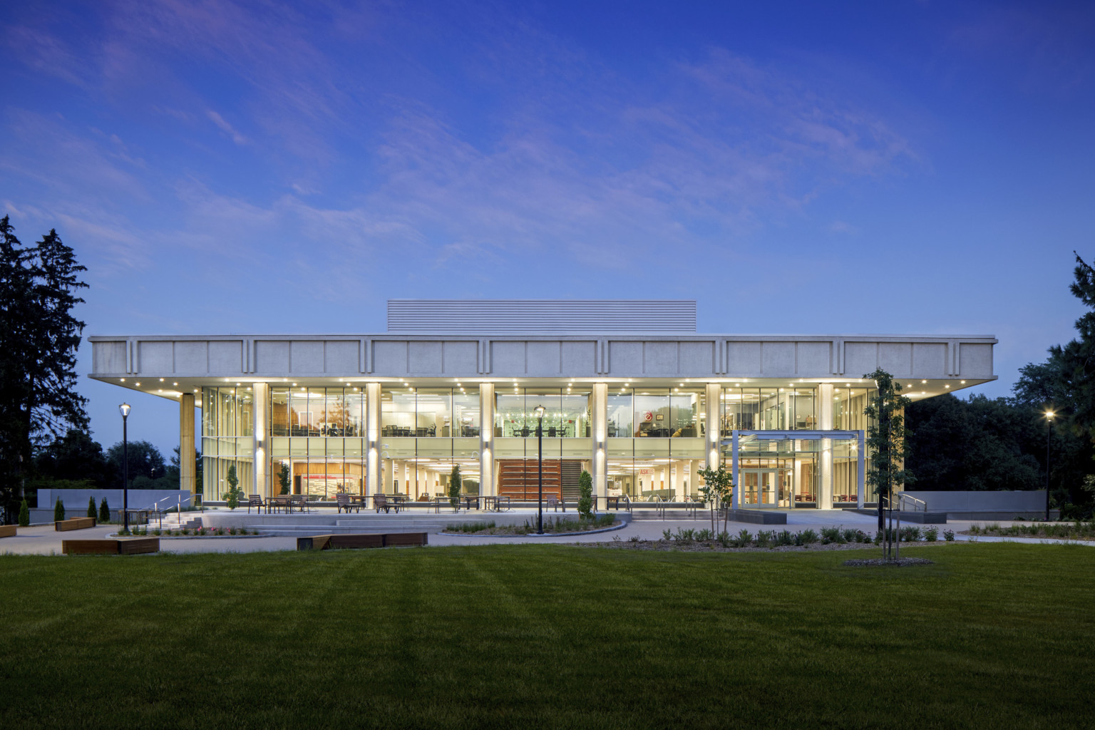 evening view of a two story academic building light up from within shining out through full glass windows evening view of a two story academic building light up from within shining out through full glass windows