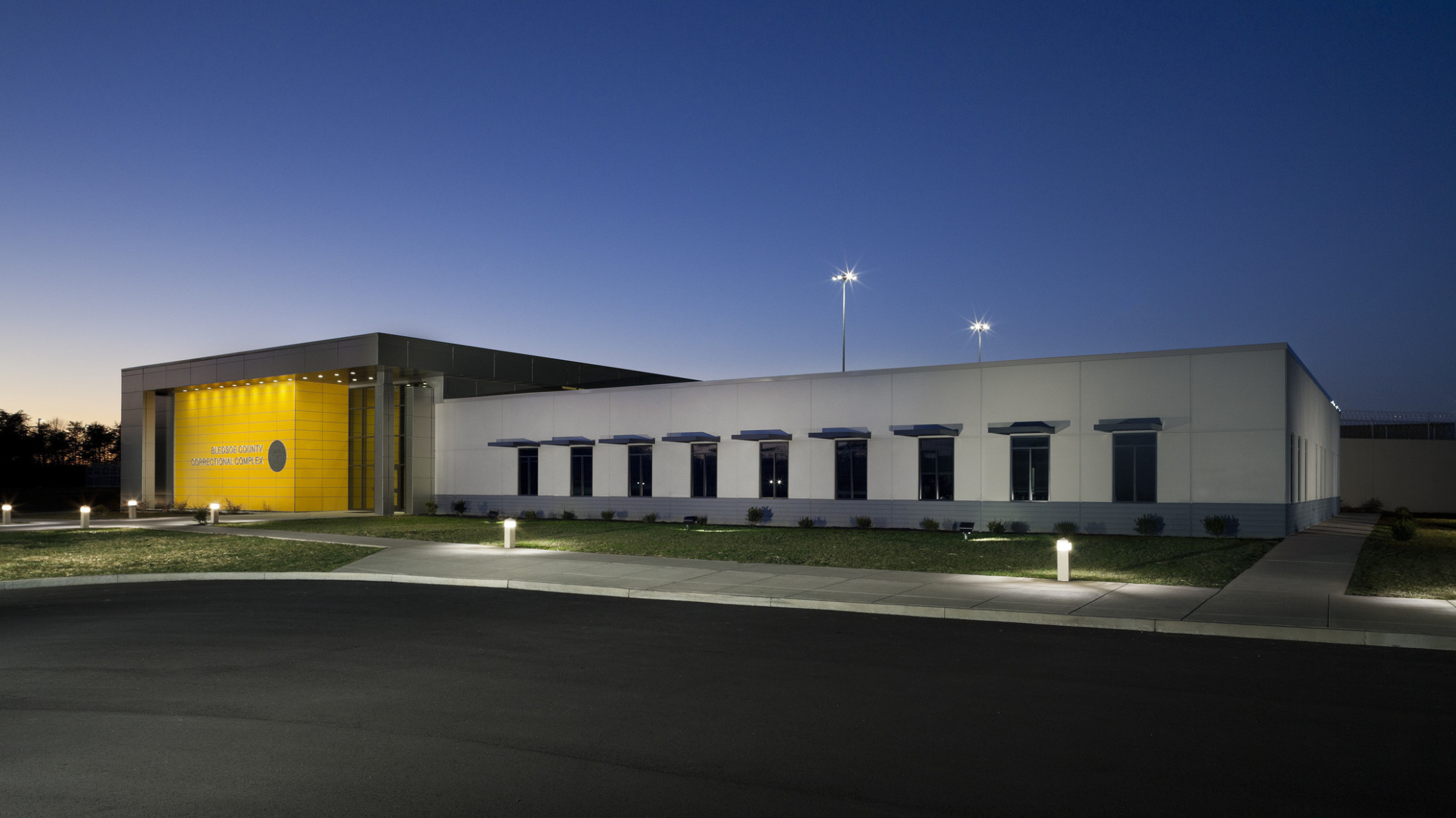 The Bledsoe County Correctional Complex exterior entryway viewed at night. Yellow accent wall is illuminated from above