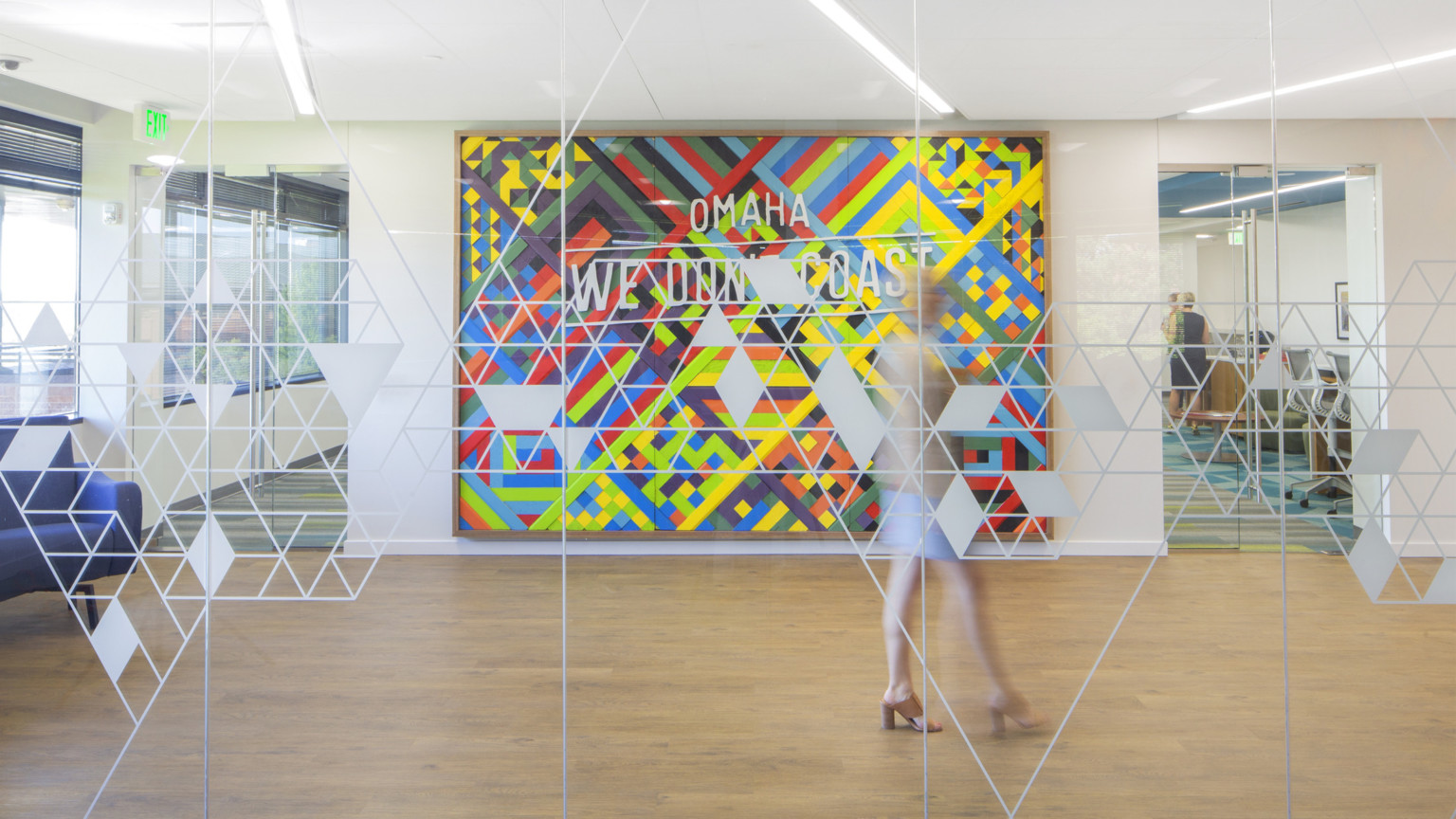 View into office common space through embossed glass. Large colorful abstract painting with words Omaha we don't coast View into office common space through embossed glass. Large colorful abstract painting with words Omaha we don't coast