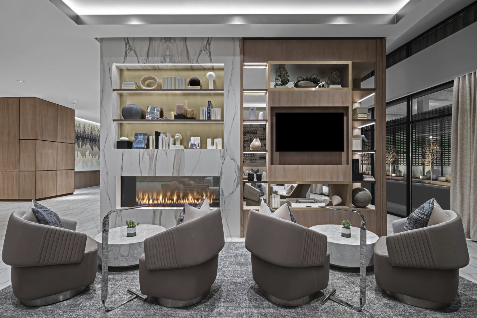 Hotel lounge with cove lighting, fireplace, bookshelf, marble, and wood paneling