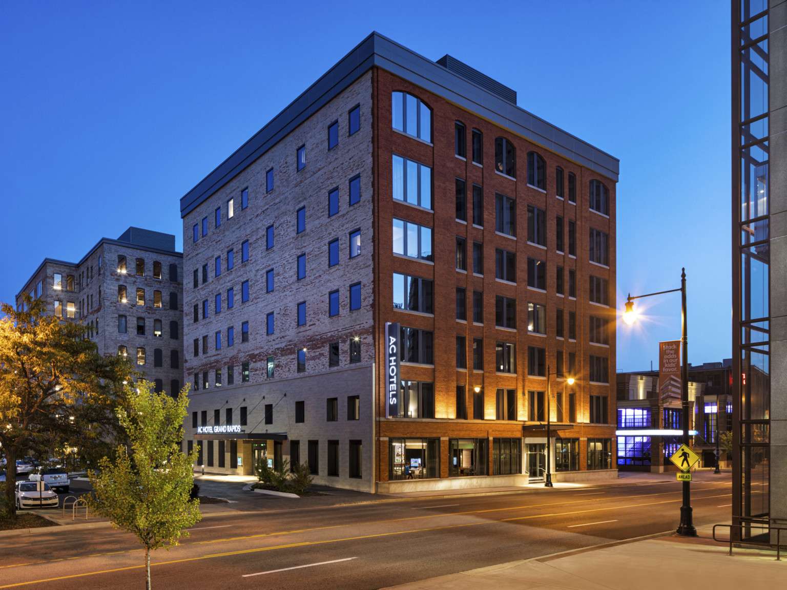 View of building corner from across the street. Main entrance on the left with stone first two stories, exposed brick on rest
