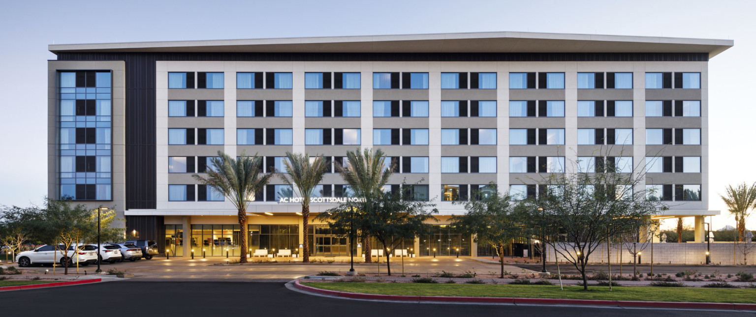 exterior design of a hotel with blue windows, white vertical panels, and palm trees out front
