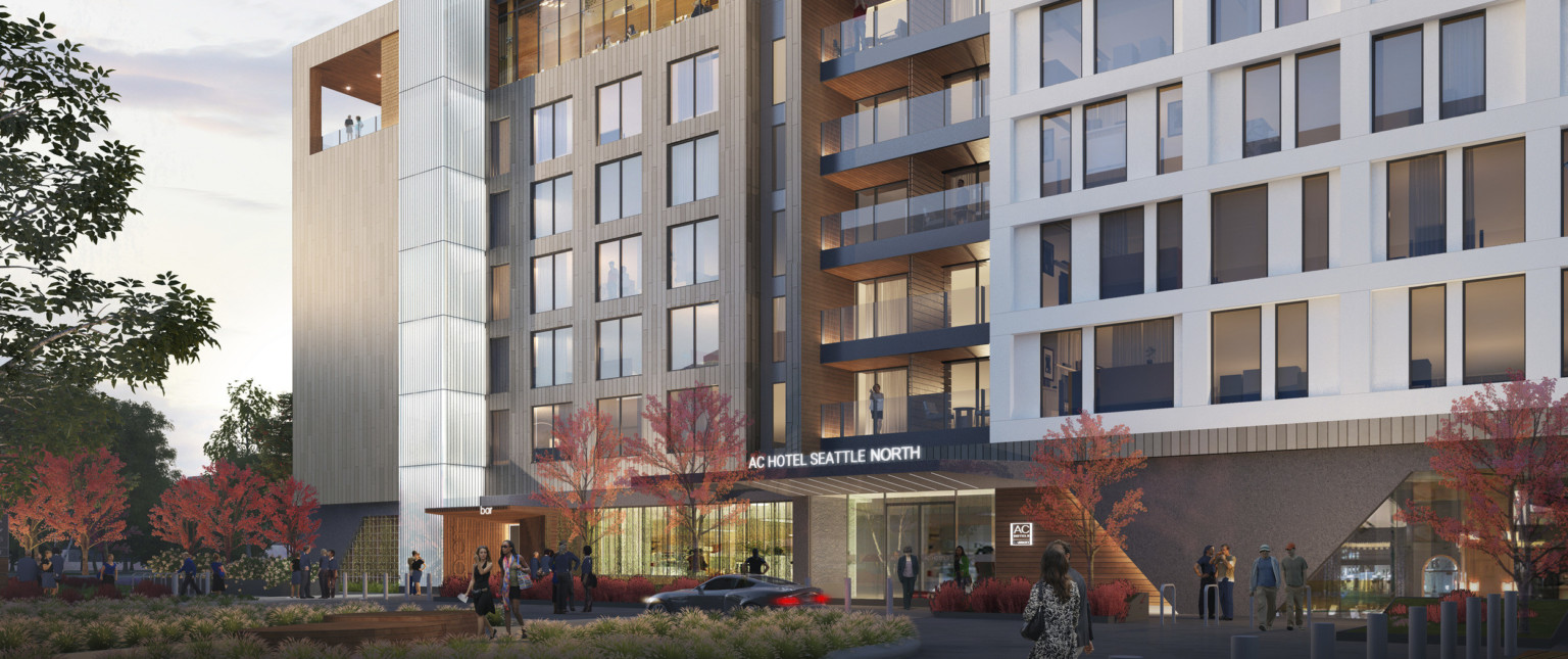 Exterior view of hotel entry with illuminated sign over doors and recessed balconies above