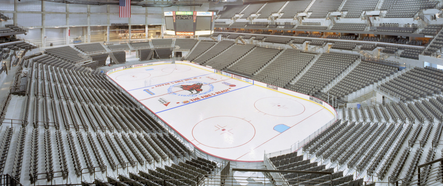 The basketball court converted to ice rink. The stadium seats are empty and their is a gap in the upper seating bowl.