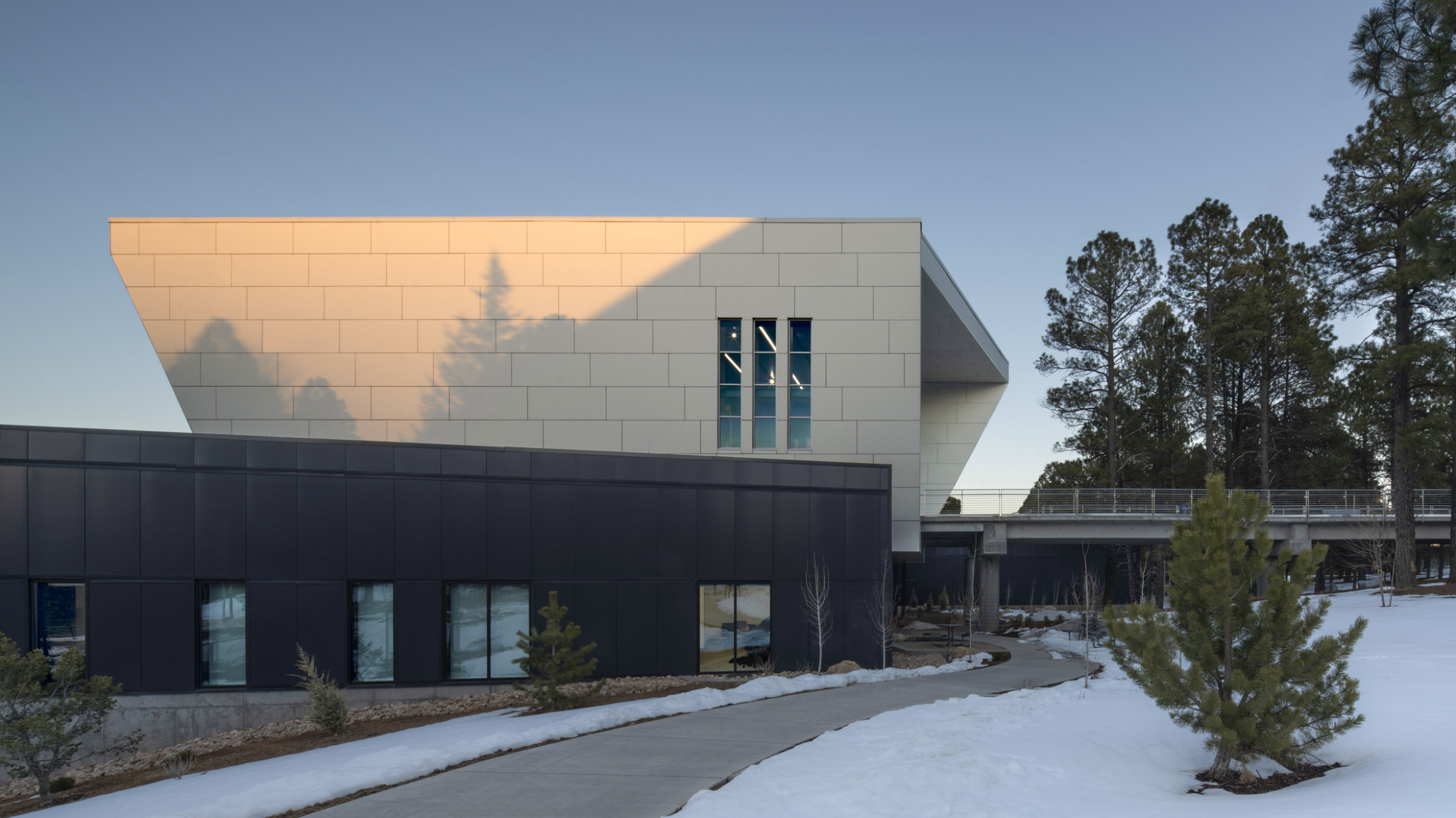 Northern Arizona University NAU student athlete center, elevated walkway with metal railings leading to white paneled wrap facade
