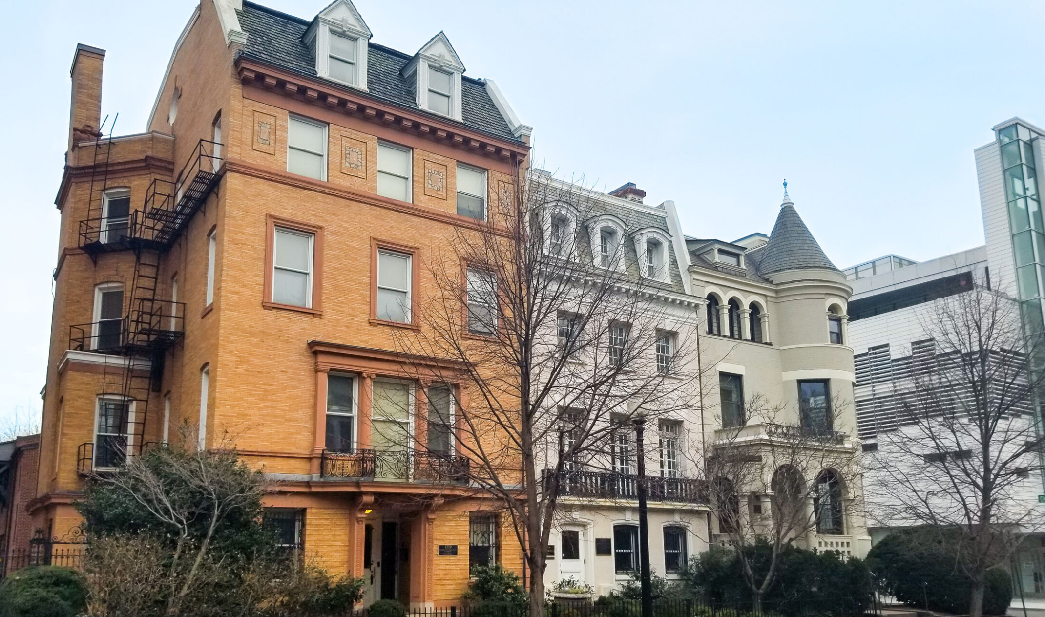 historic row houses in Washington DC, the leftmost being a warm orange revival brick façade. Turret on far right building