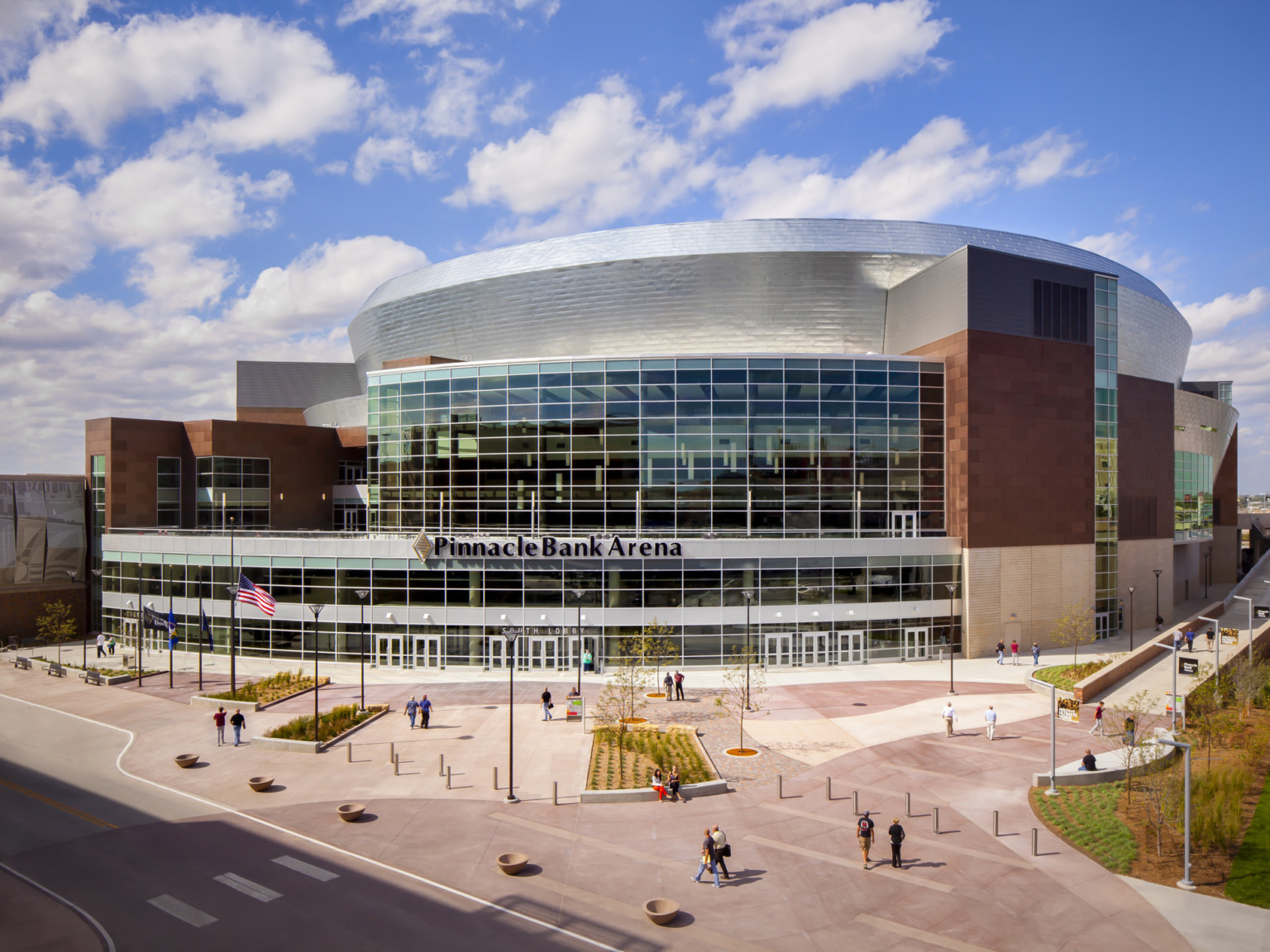 Exterior of venue with Pinnacle Bank Arena sign, a rounded multi story building with large windows and silver roof