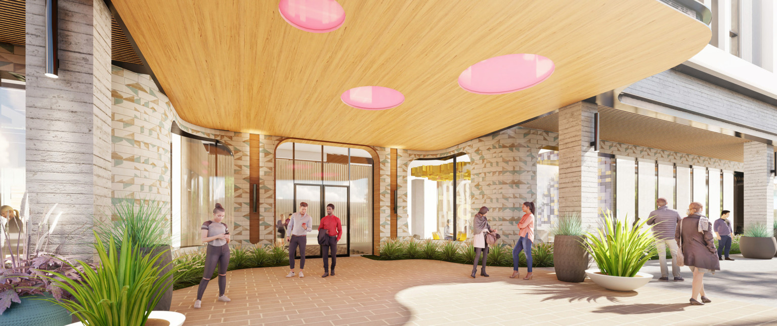 Tiled entrance to mixed-use facility with large windows under wood canopy with pink circles. Plants line building