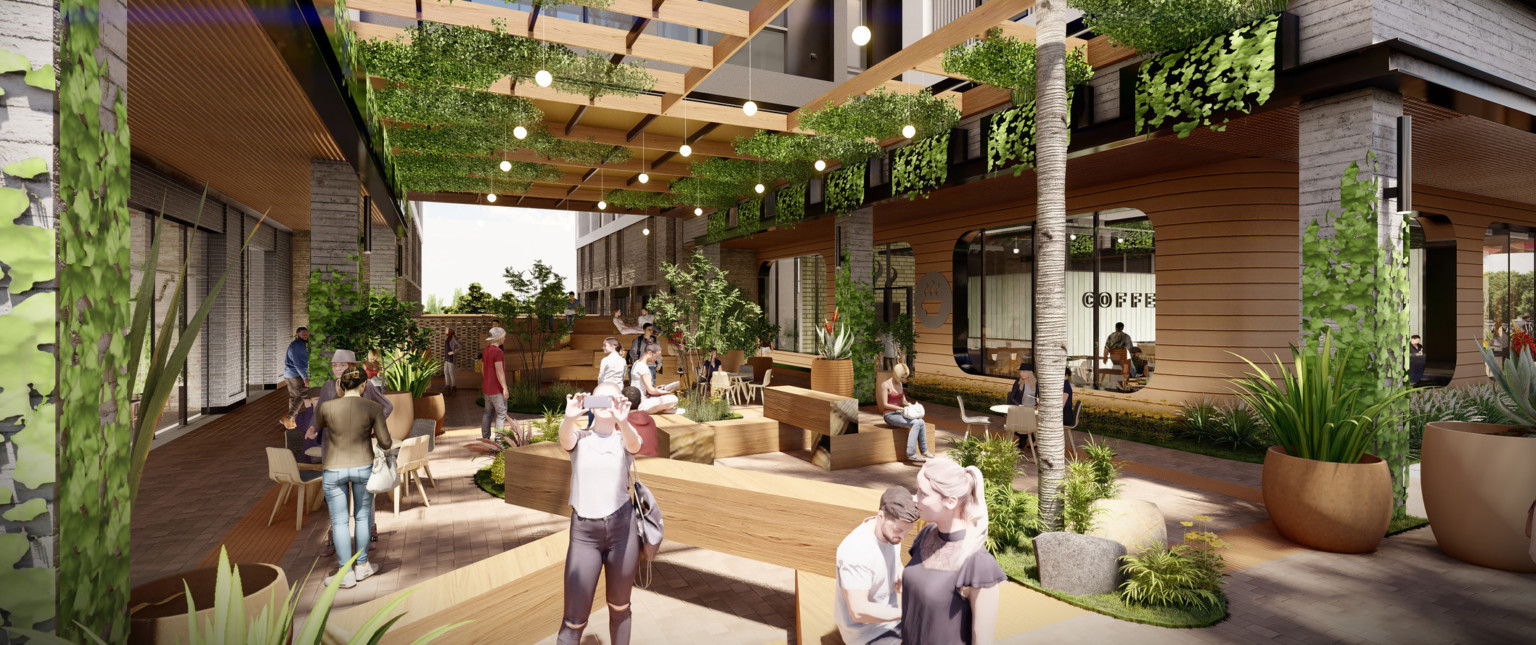 View from under canopy frame with hanging greenery and landscaped plants. Wood benches, chairs, tables, in common space