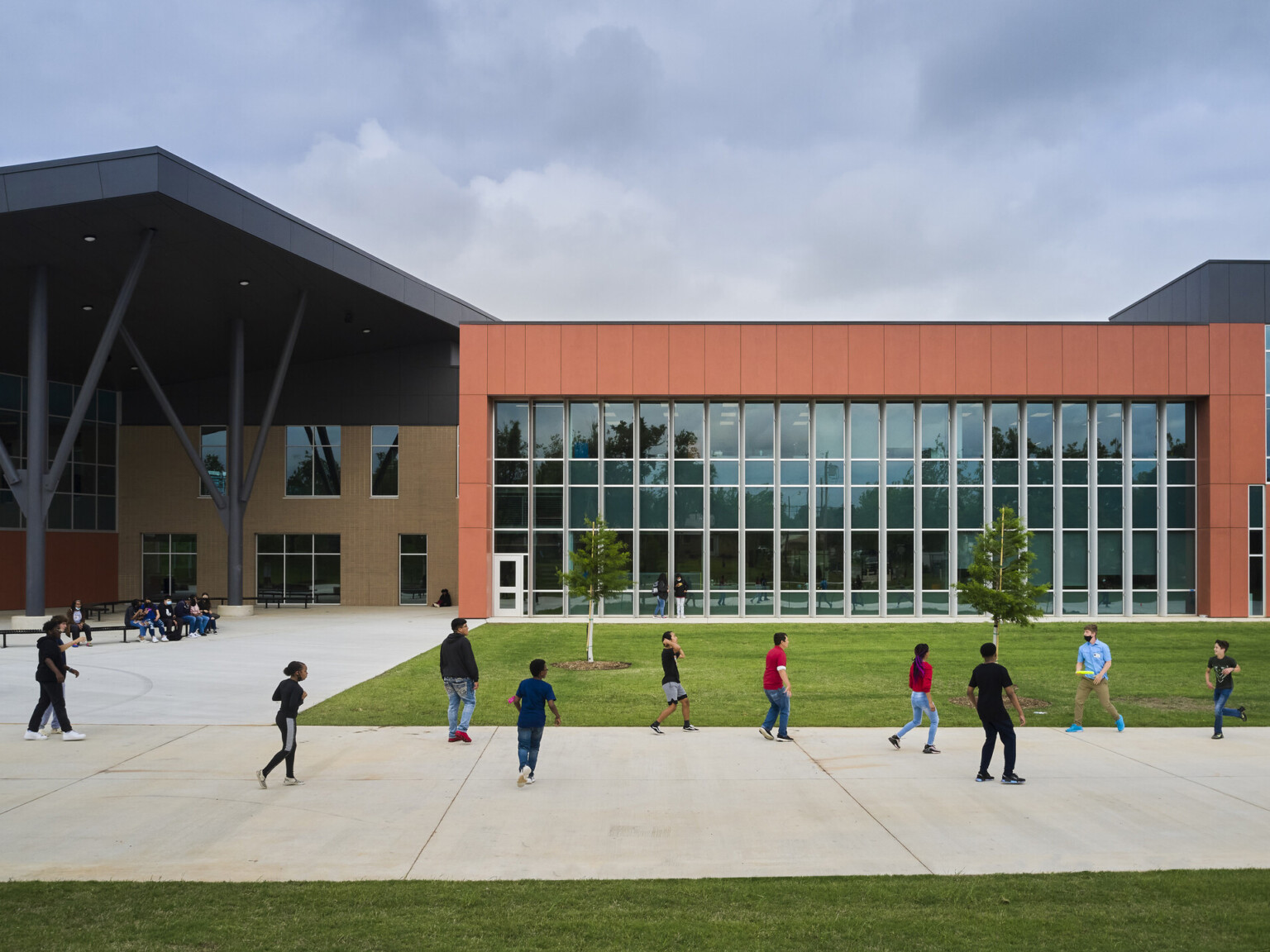 James L. Capps Middle School exterior with angled black shelter brick building. Orange wrap facade over double height glass